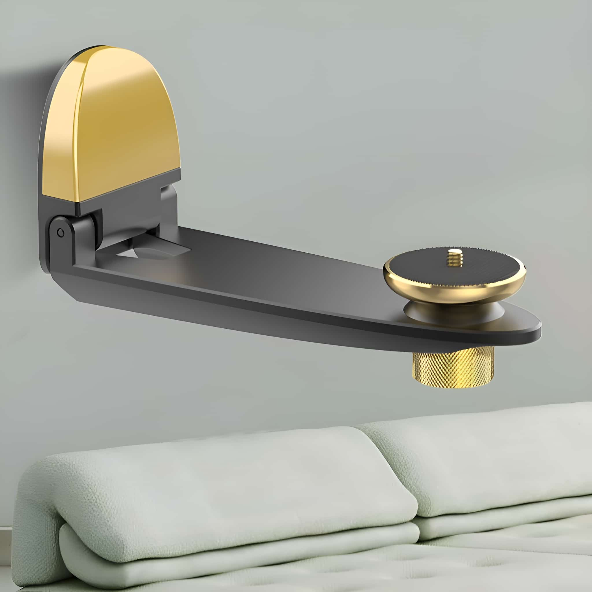 Schwarz-goldene Wandhalterung für eine Kamera, an einer grauen Wand über einem weißen Sofa.