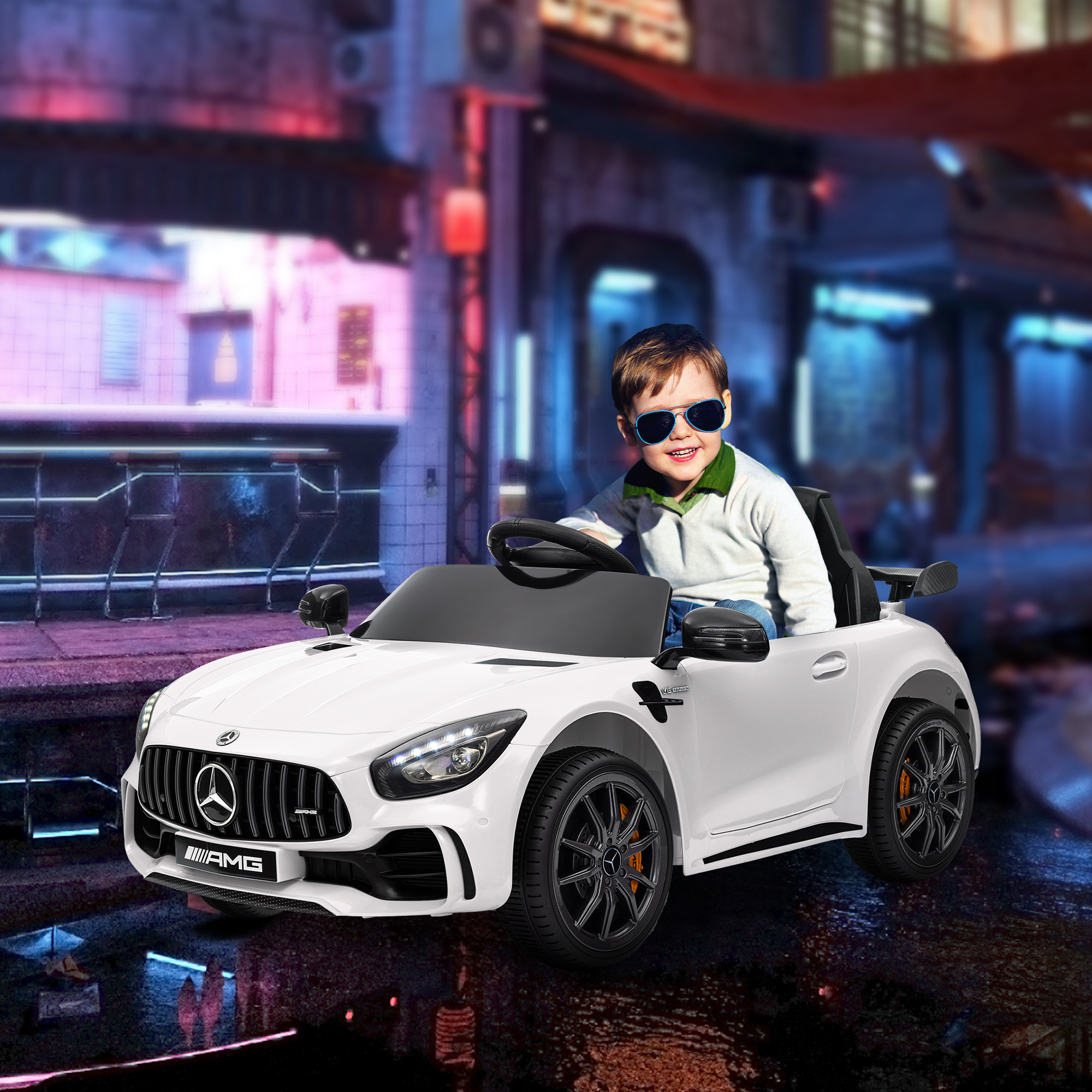 Niño en coche de juguete blanco, con gafas de sol. Coche blanco con detalles negros, fondo de ciudad.