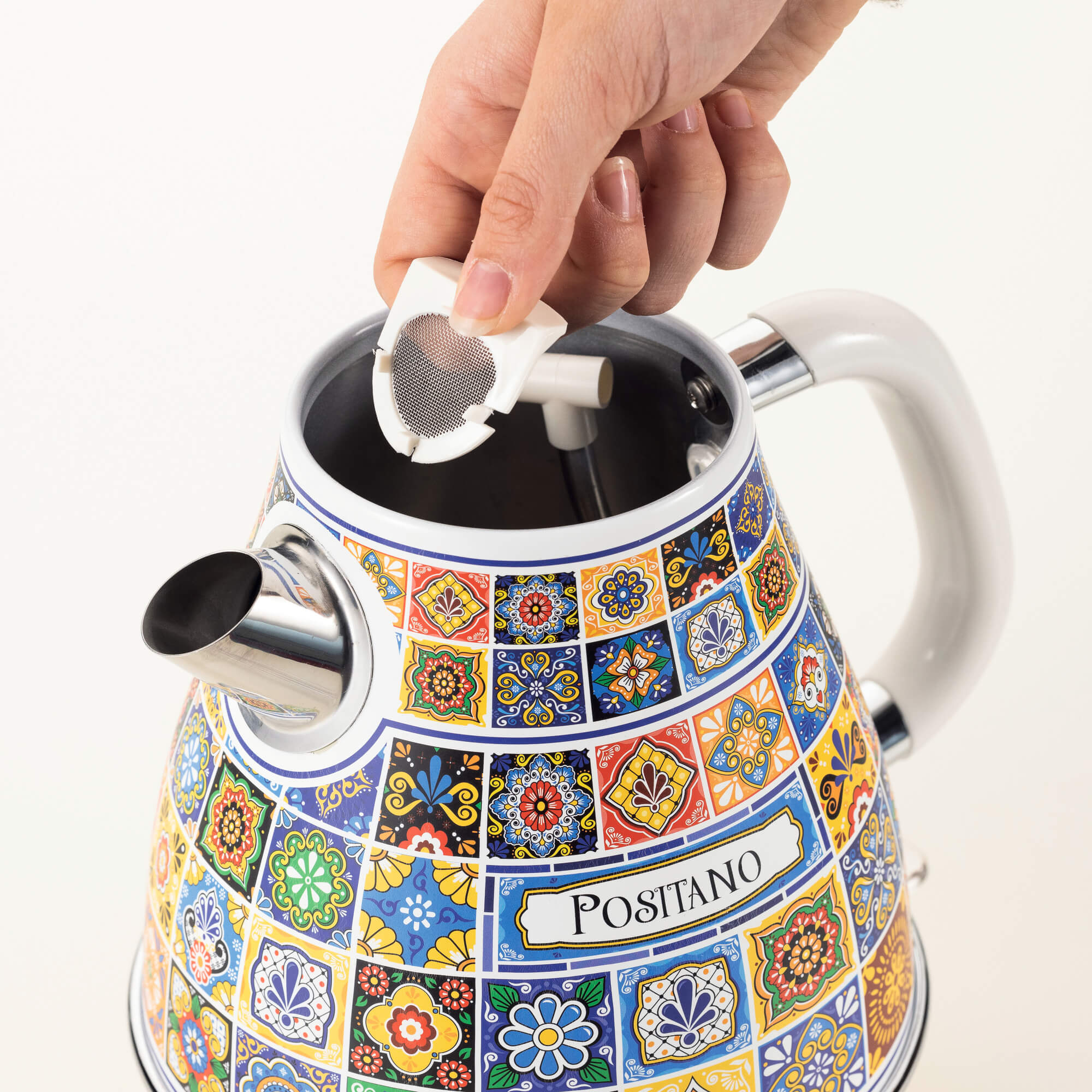 Osoba wlewa wodę z sitka do czajnika w wzory z białymi akcentami.