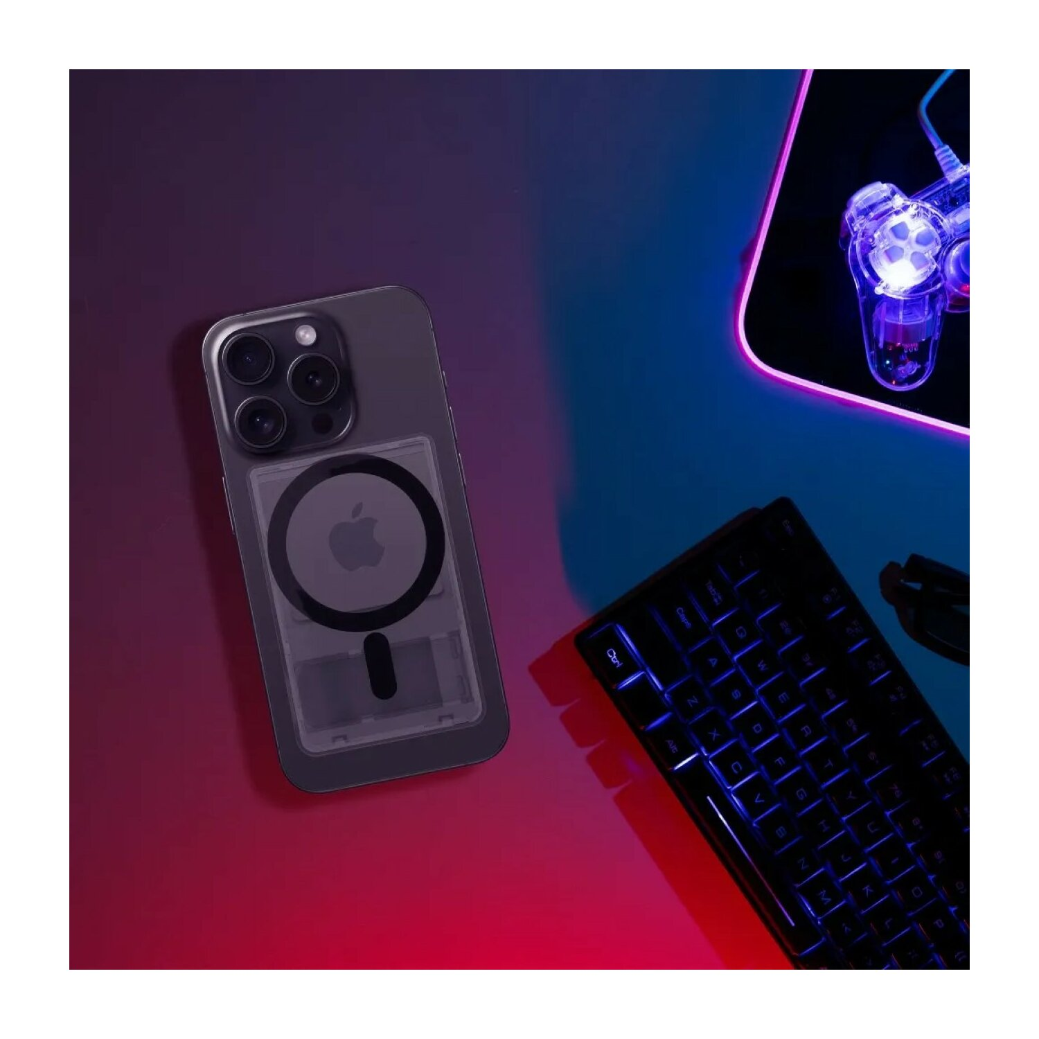 Ein iPhone in einer durchsichtigen Hülle mit MagSafe-Ring, Tastatur und Gaming-Maus auf einem Schreibtisch mit Farblicht.