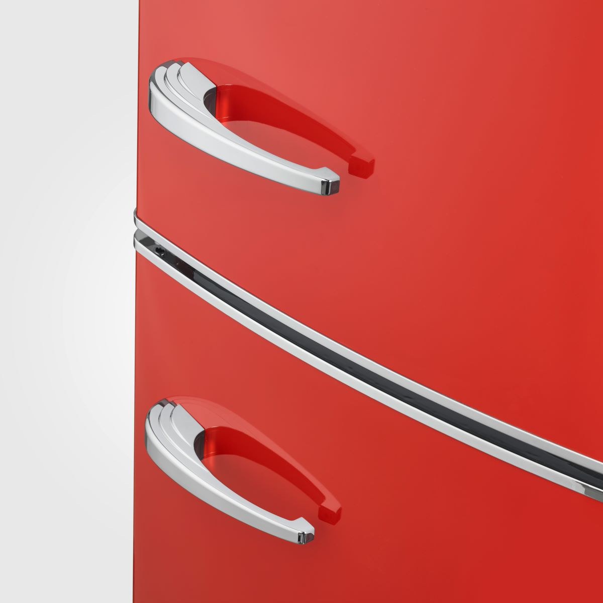 Czerwona lodówka ze srebrnymi uchwytami. Dwa uchwyty są na górze, a jeden pośrodku.