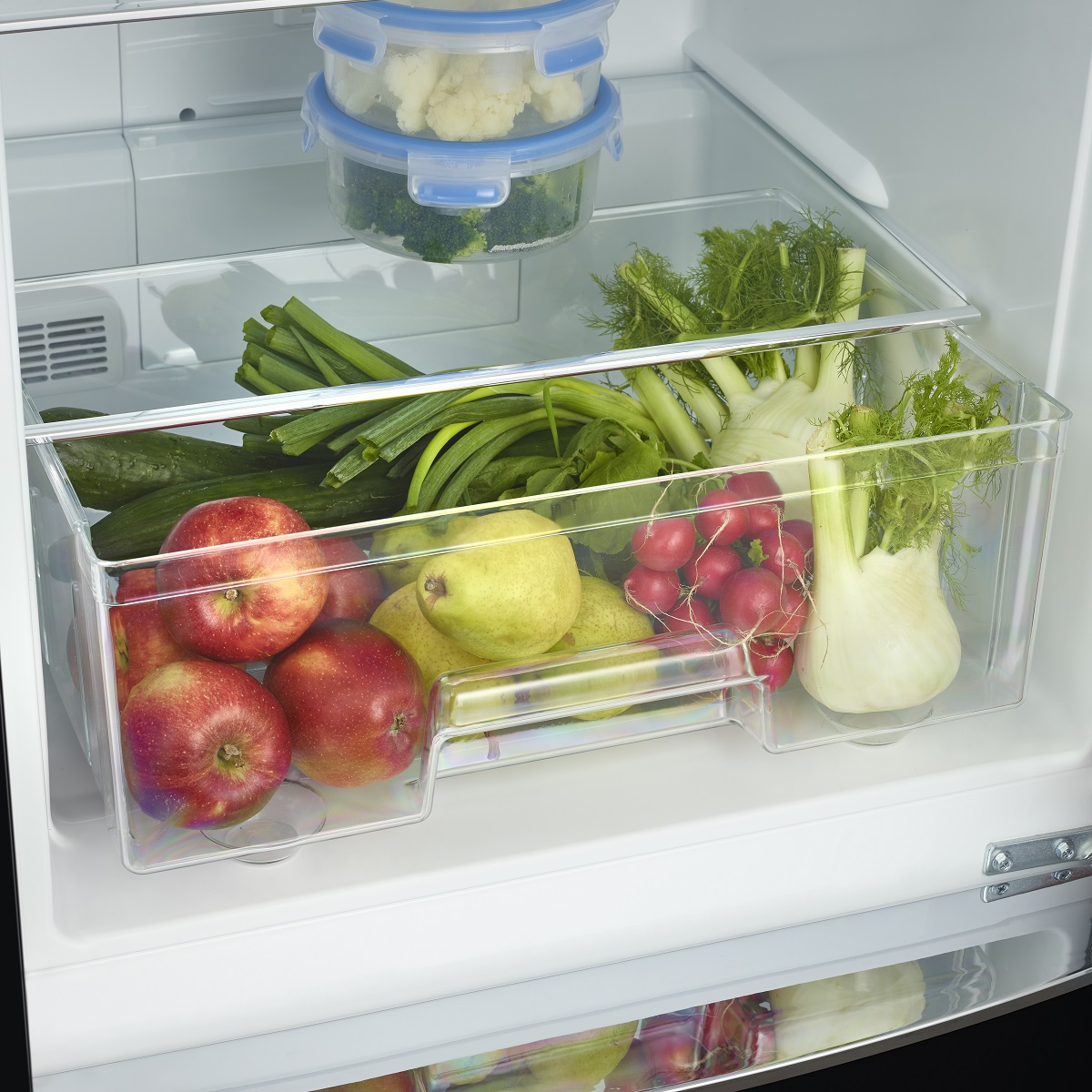 Refrigerator interior with fruit and vegetables in drawers. White interior.