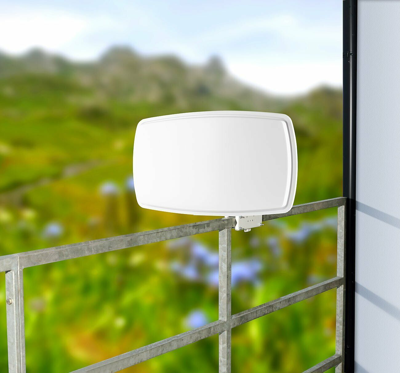 Eine weiße Antenne, die an einem Metallzaun befestigt ist, mit grünem Hintergrund.