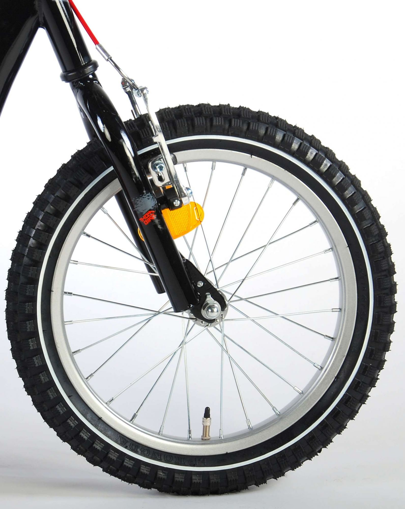 Nahaufnahme eines Fahrradrads. Das Rad hat einen schwarzen Reifen, eine silberne Felge und einen gelben Reflektor.