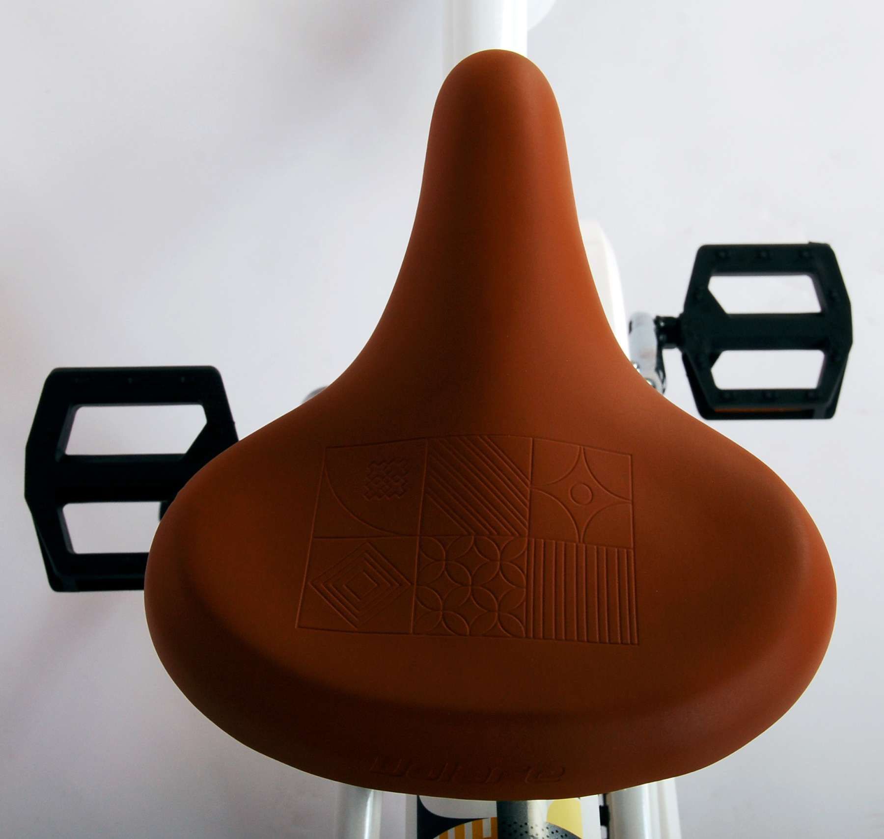 Nahaufnahme eines braunen Fahrradsattels mit gemustertem Design, mit Pedalen.