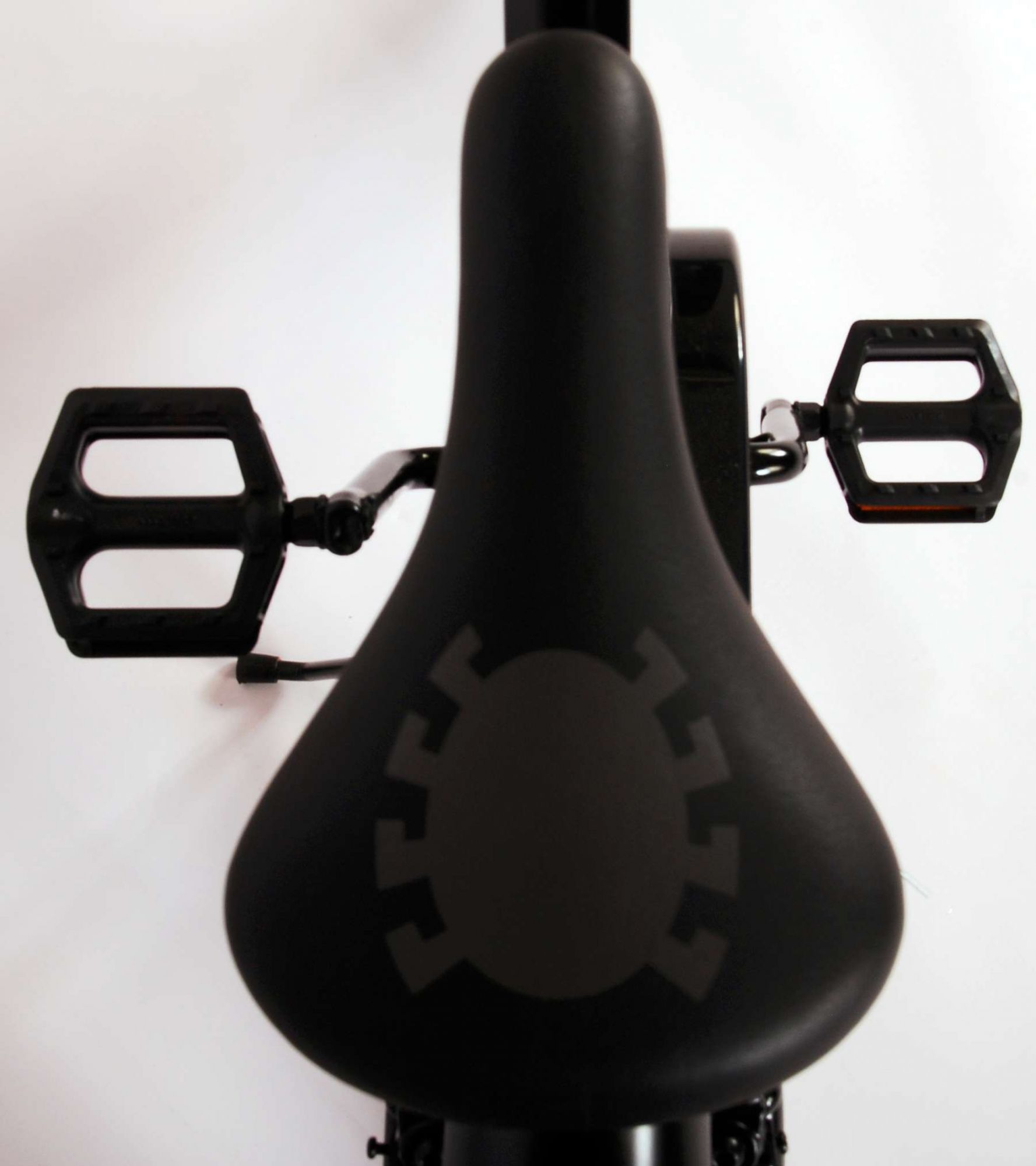 Schwarzer Fahrradsattel mit schwarzen Pedalen. Der Sitz hat ein graues Zahnradlogo.