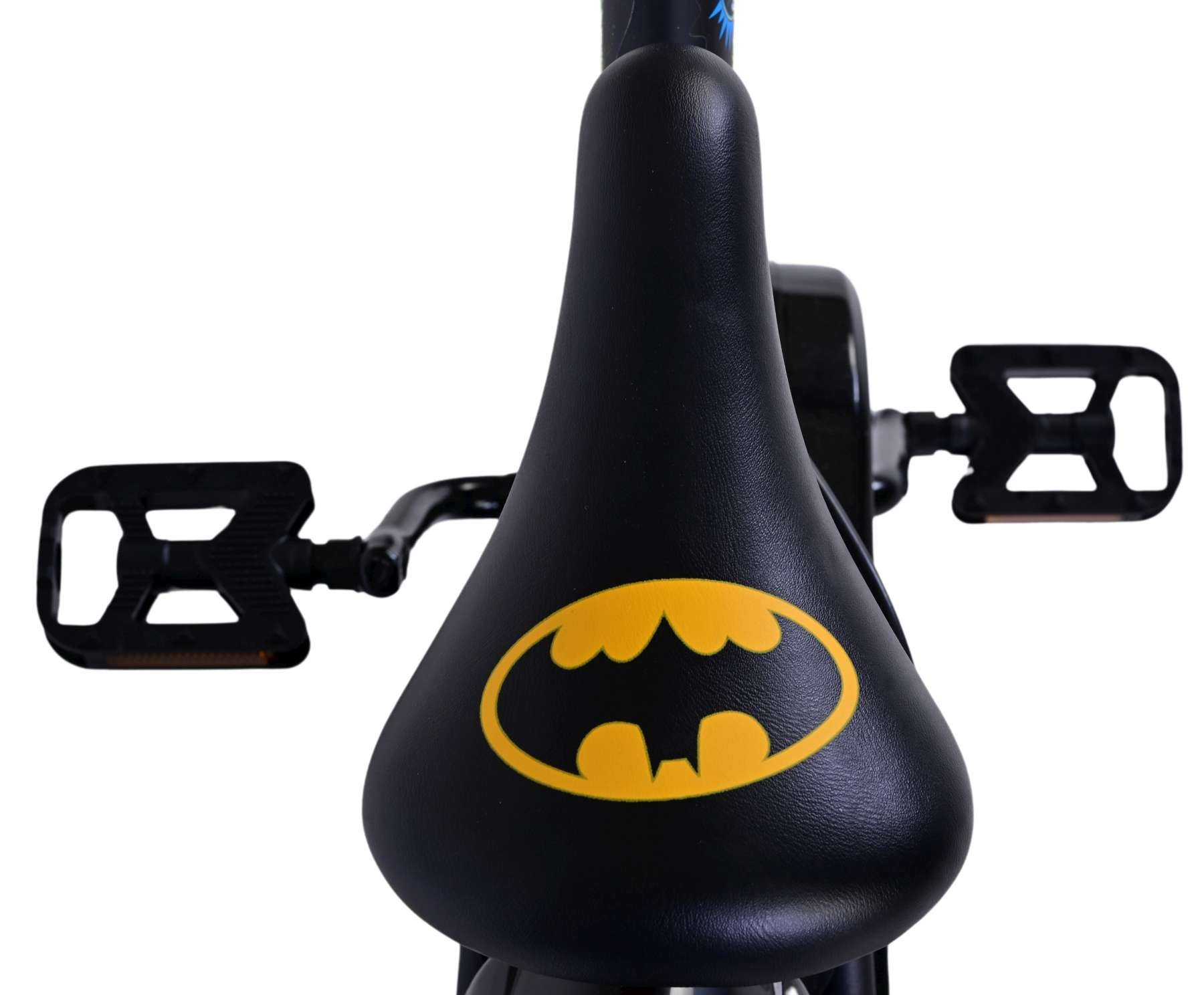 Nahaufnahme eines schwarzen Fahrradsattels mit gelbem Batman-Logo. Schwarze Pedale sind sichtbar.