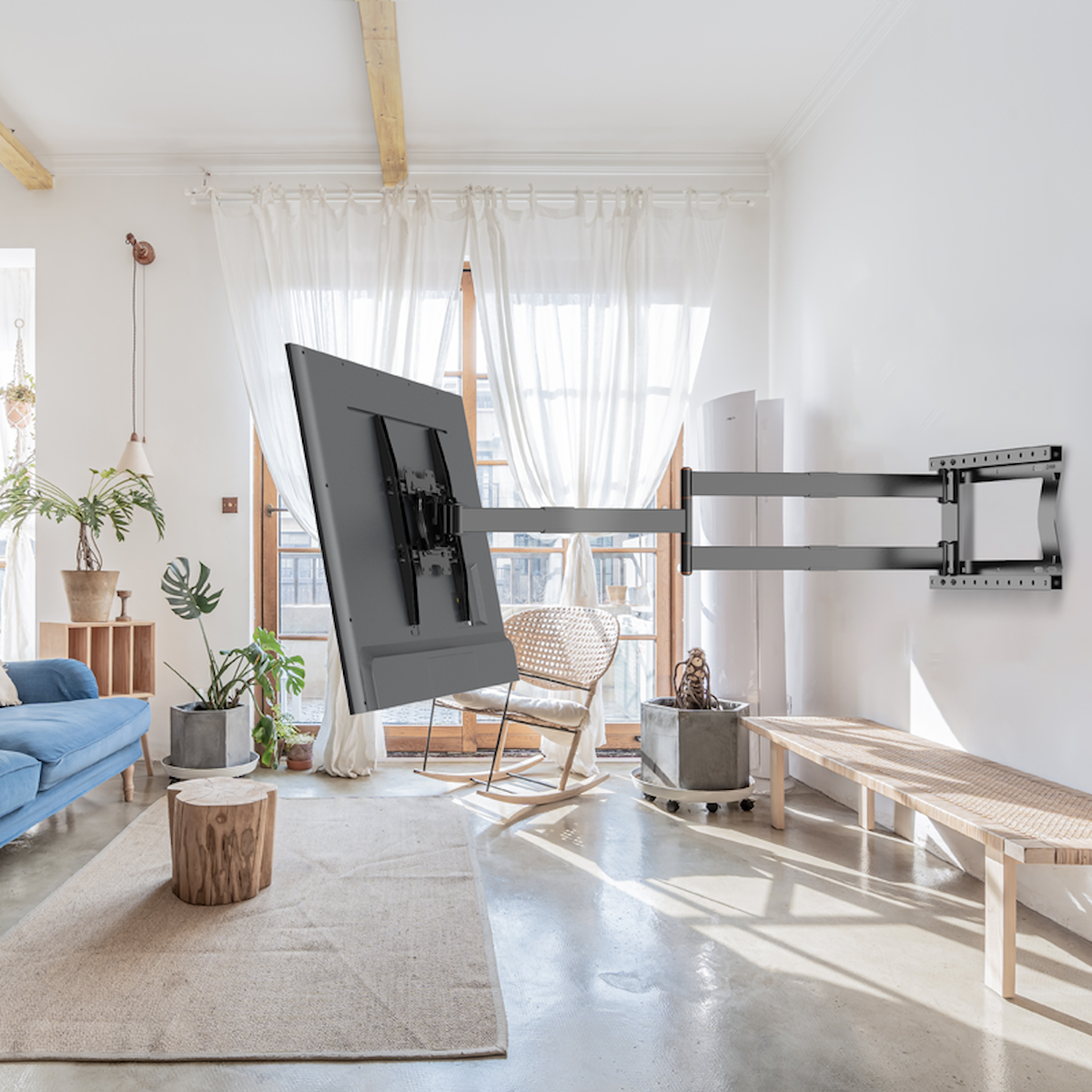 Een kamer met een grote tv aan de muur. Een blauwe bank, planten en een kleed zijn ook in de kamer.