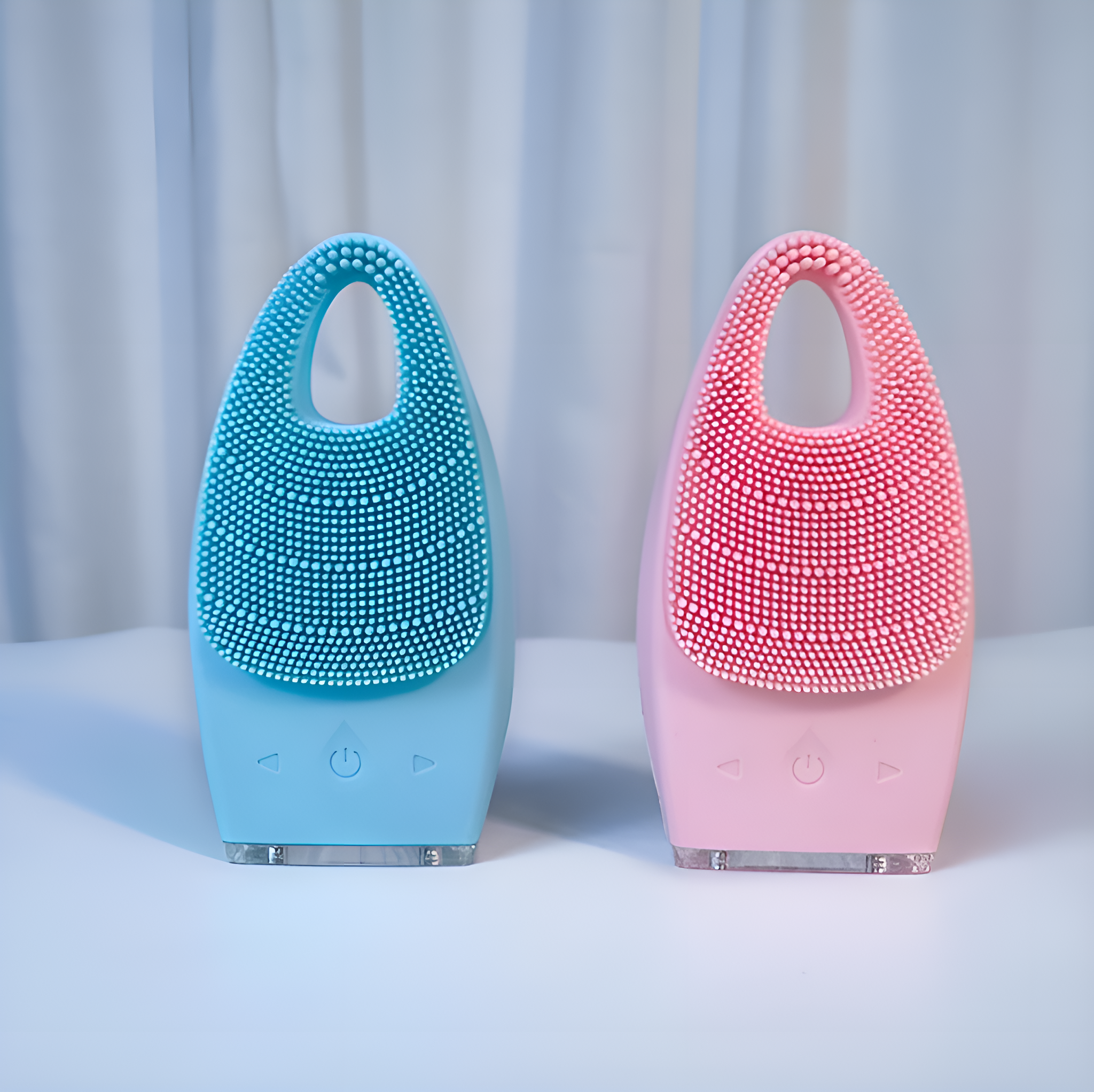 Zwei blaue und rosa Gesichtsreinigungsgeräte auf weißer Oberfläche, vor weißem Hintergrund.