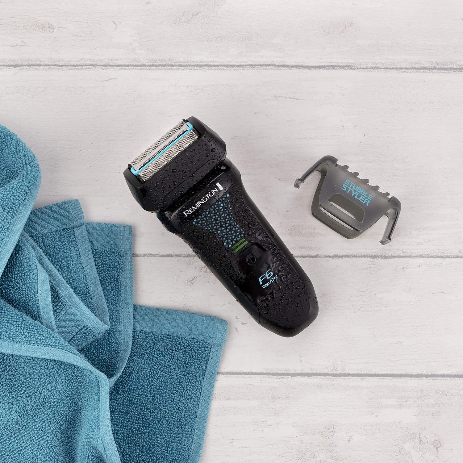 Remington elektrisch scheerapparaat met stoppeltjes styler en een blauwe handdoek.