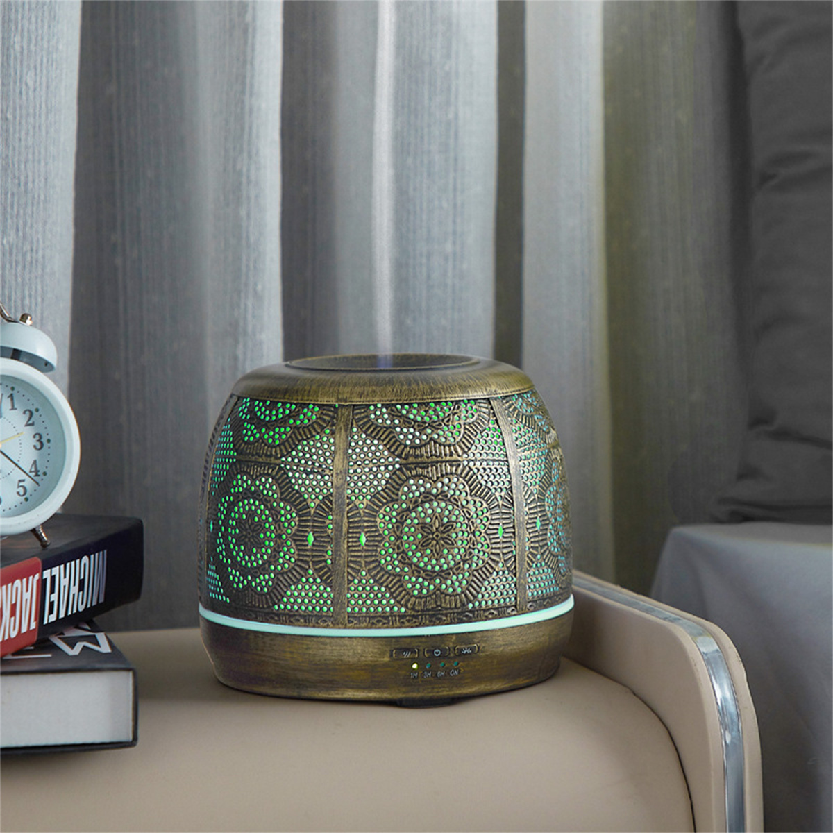 Dekorativer Öldiffusor mit Bronze-Finish und grüner Beleuchtung, auf einem Tisch.