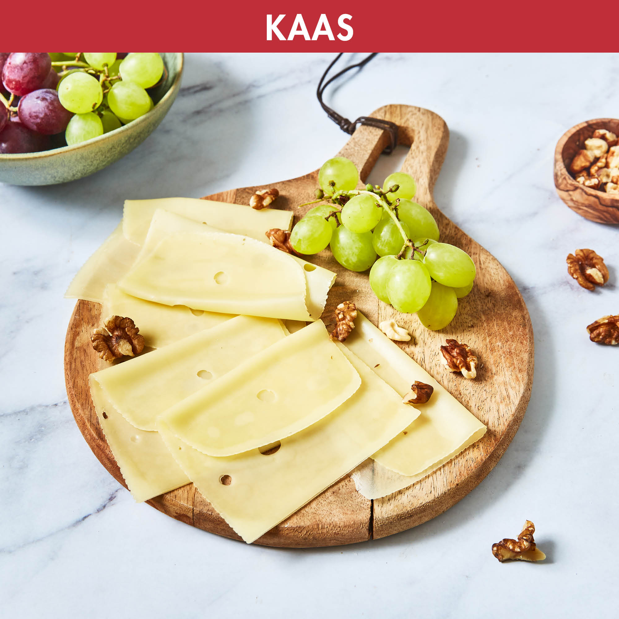 Tranches de fromage, raisins et noix sur une planche en bois. Le fromage est tranché et les raisins sont verts.