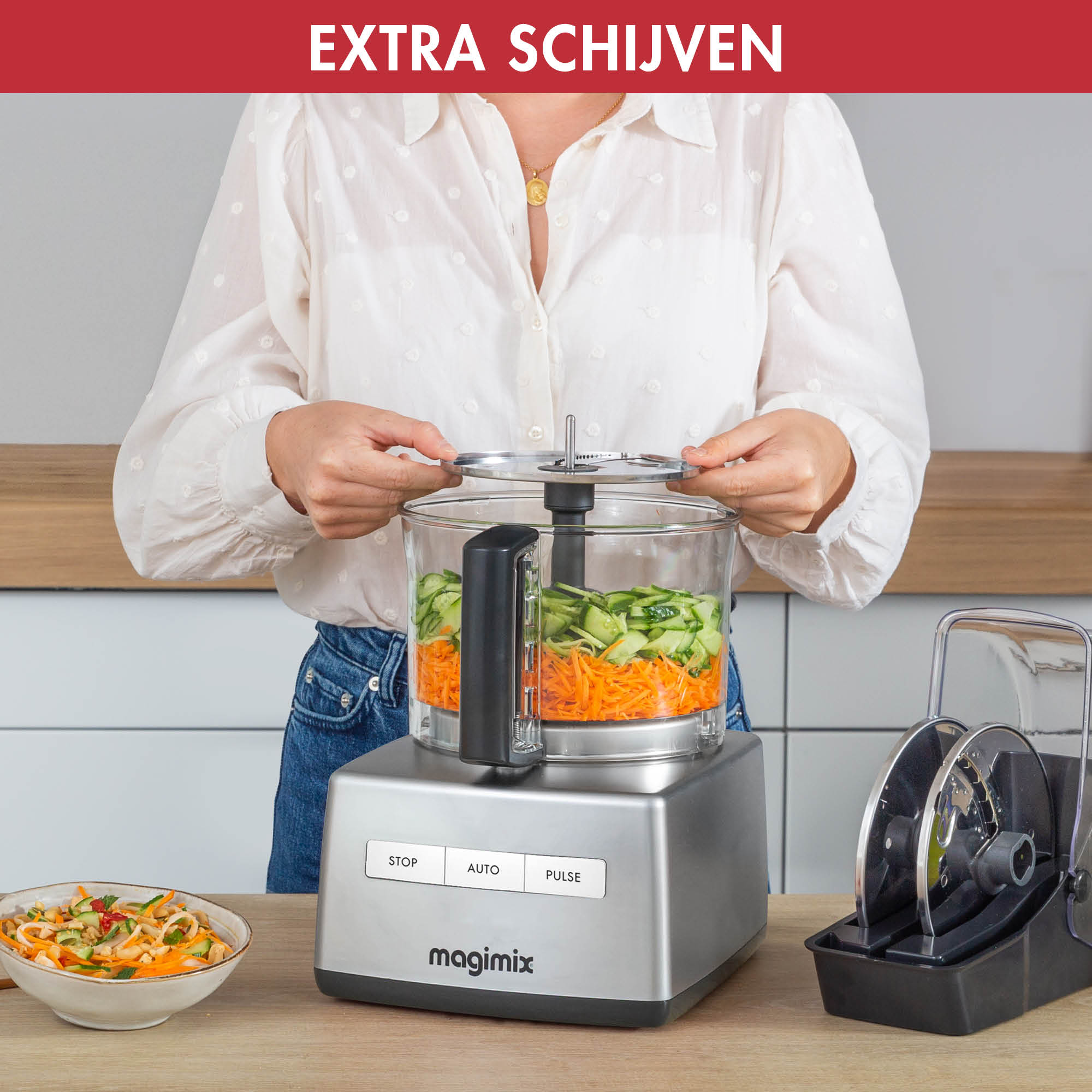 Person is using a food processor, with prepared vegetables and extra blades.