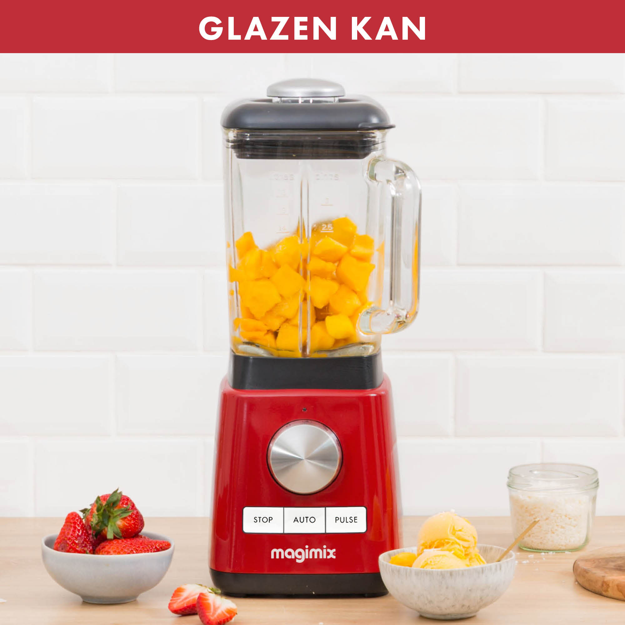 Rode blender met gele mango's erin, en kommen met aardbeien en ijs.