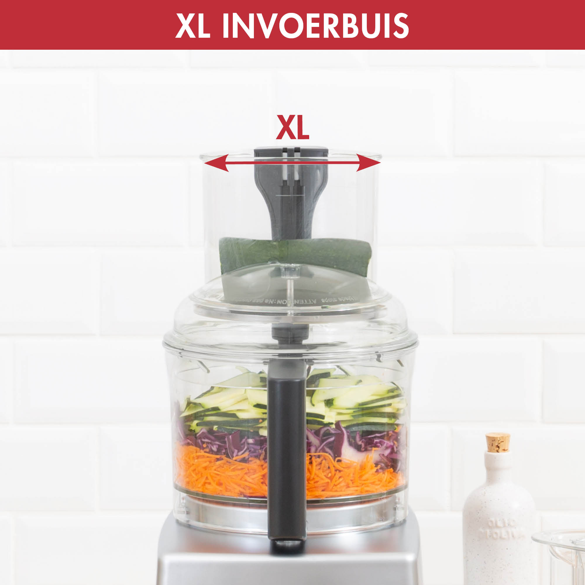 A food processor is shown with vegetables inside. The top has an XL input and a zucchini.
