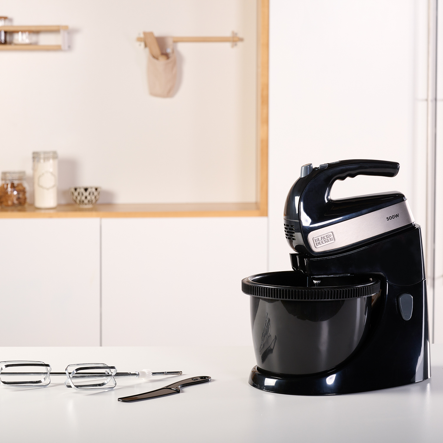 Czarny i srebrny mikser stojący z misą i przystawkami na białym blacie.