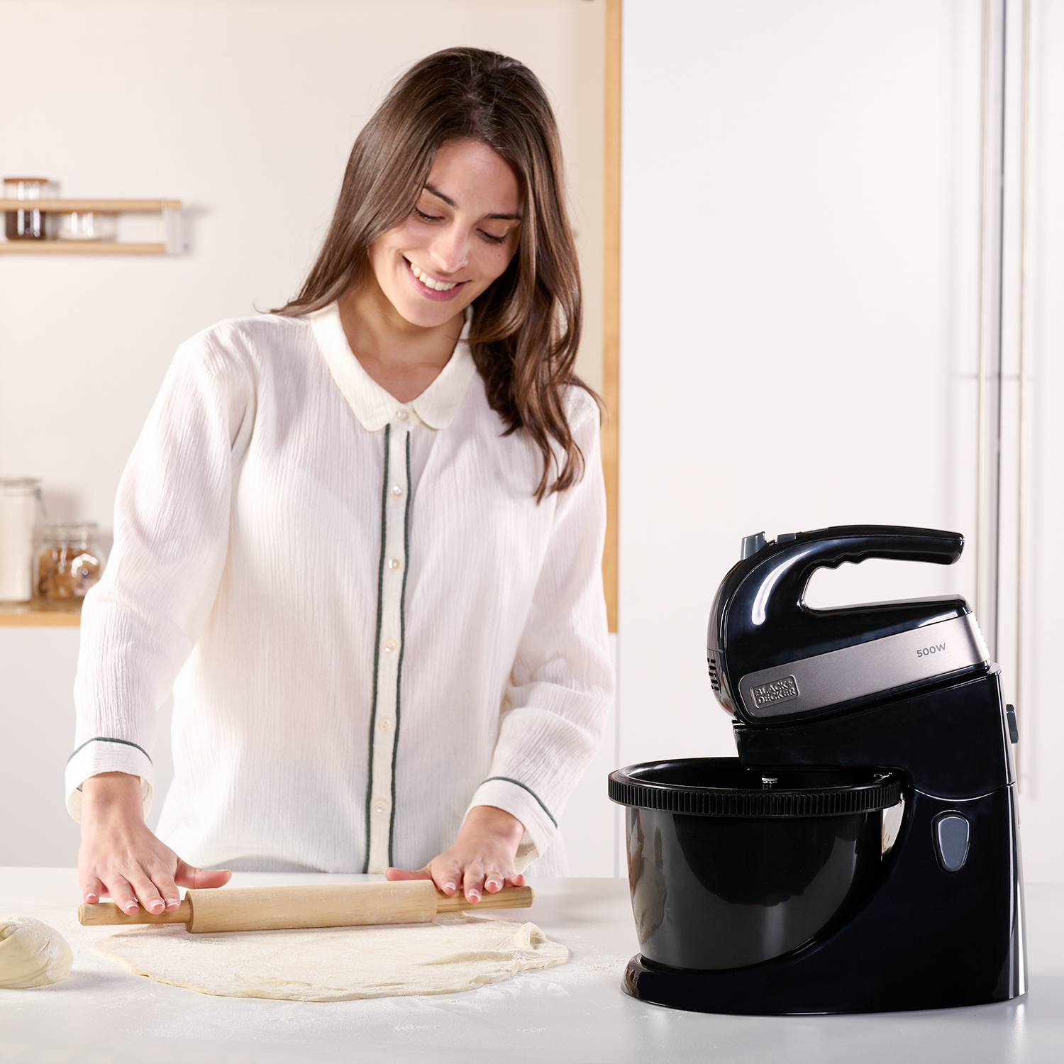 Kobieta wałkuje ciasto wałkiem obok czarnego miksera.