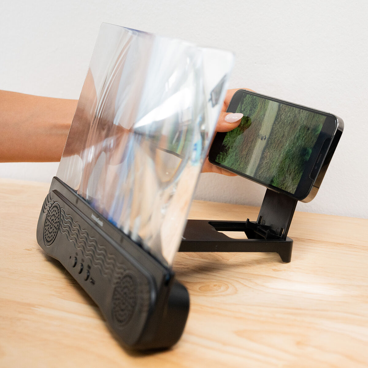 Mujer usando un teléfono con un magnificador de pantalla sobre una mesa de madera.