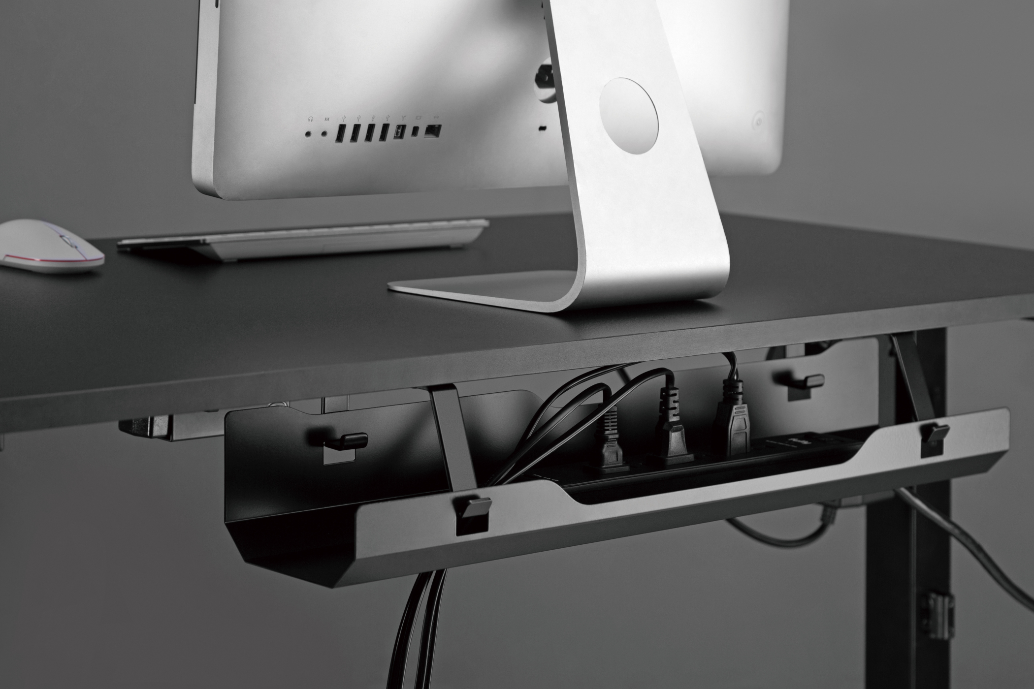 Een bureau met een computermonitor, toetsenbord en kabels verborgen in een lade.