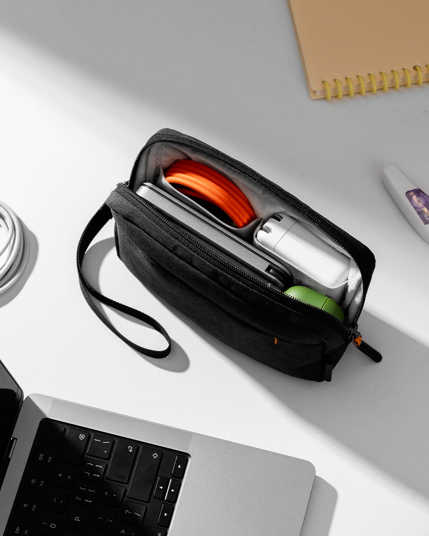 Eine schwarze Reisetasche mit Reißverschluss, die einen Laptop, ein Ladegerät und anderes technisches Zubehör enthält.