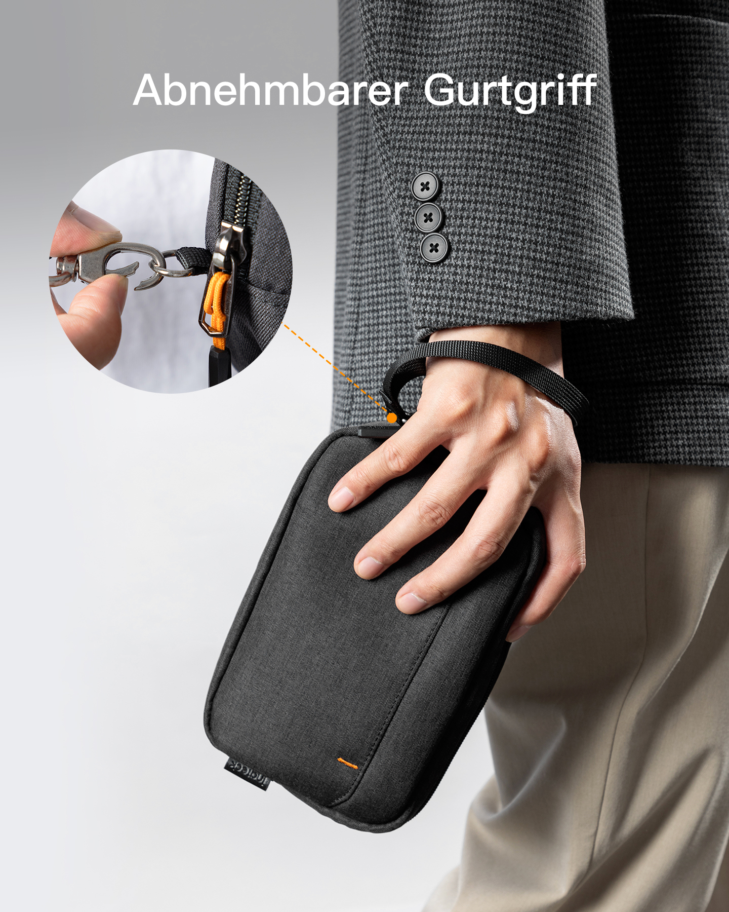 Eine Person hält eine schwarze Tasche mit orangefarbenem Akzent und zeigt, wie man den Gurt abnimmt.