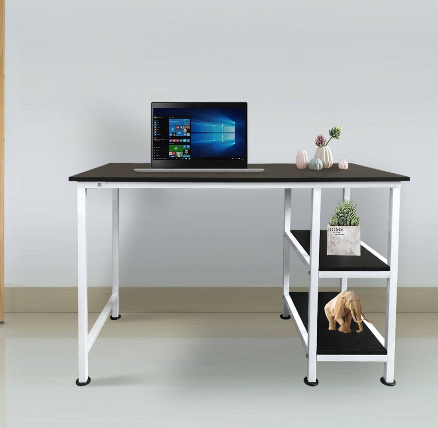 Zwart bureau met witte poten, een laptop, decoratie en een plank met items, witte muur.