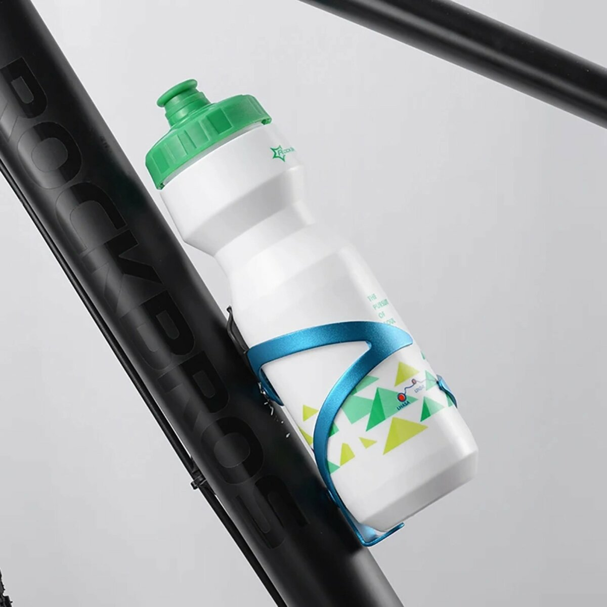 Weiße Wasserflasche mit grünem Deckel, in blauem Fahrradhalter, an schwarzem Fahrradrahmen.