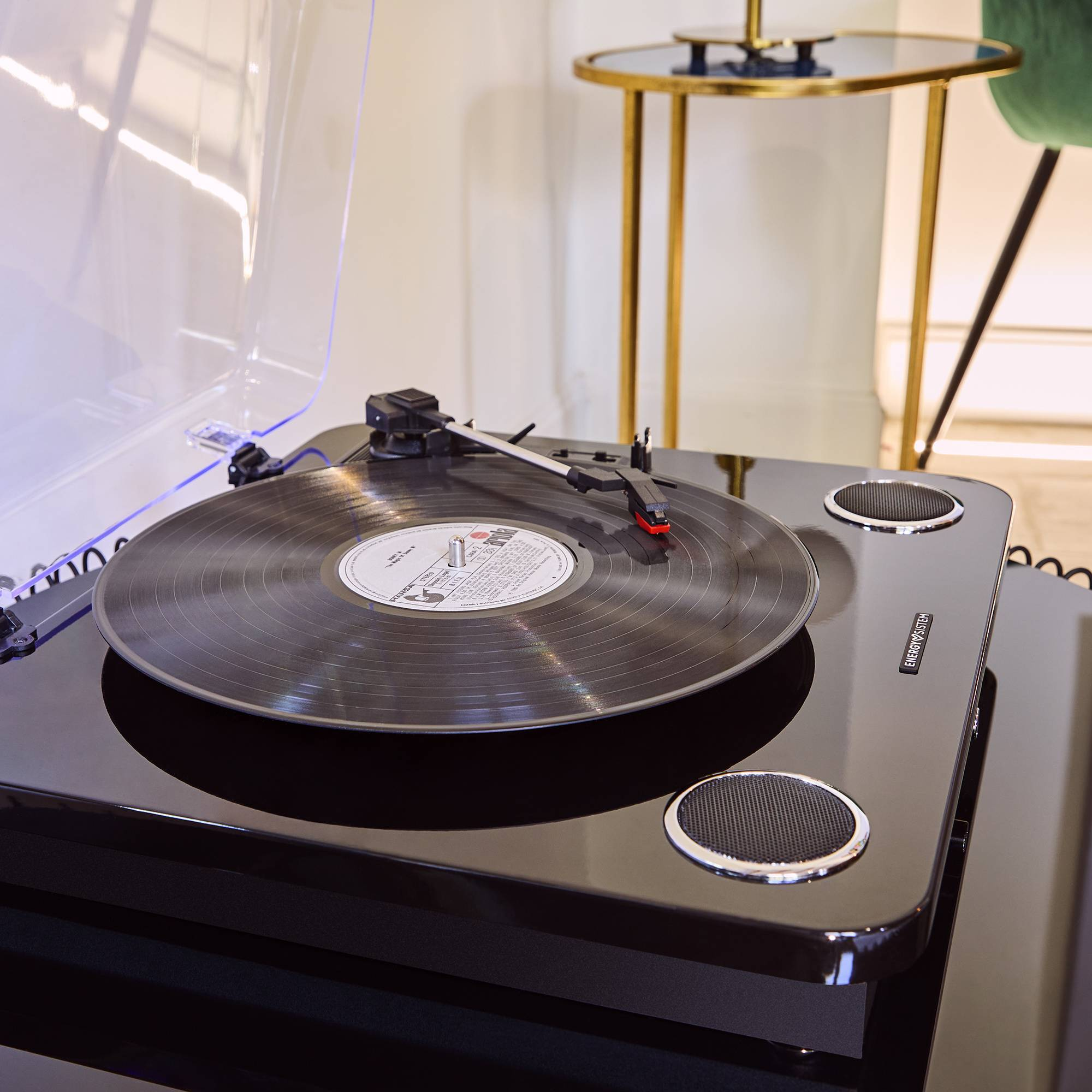 Tocadiscos negro con disco de vinilo reproduciéndose. Altavoces y otros elementos visibles.
