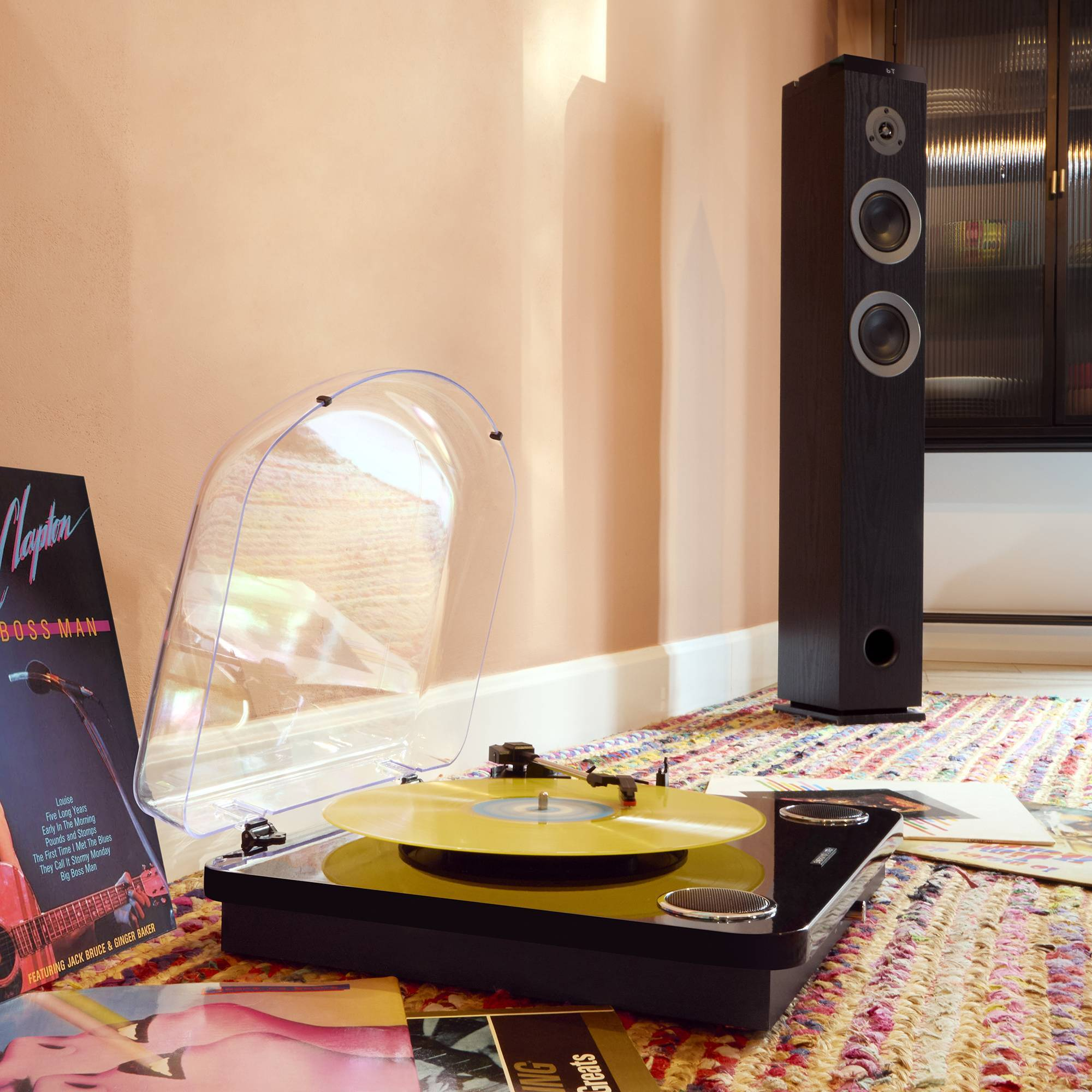 Un reproductor de vinilo con un disco amarillo sobre una alfombra colorida.