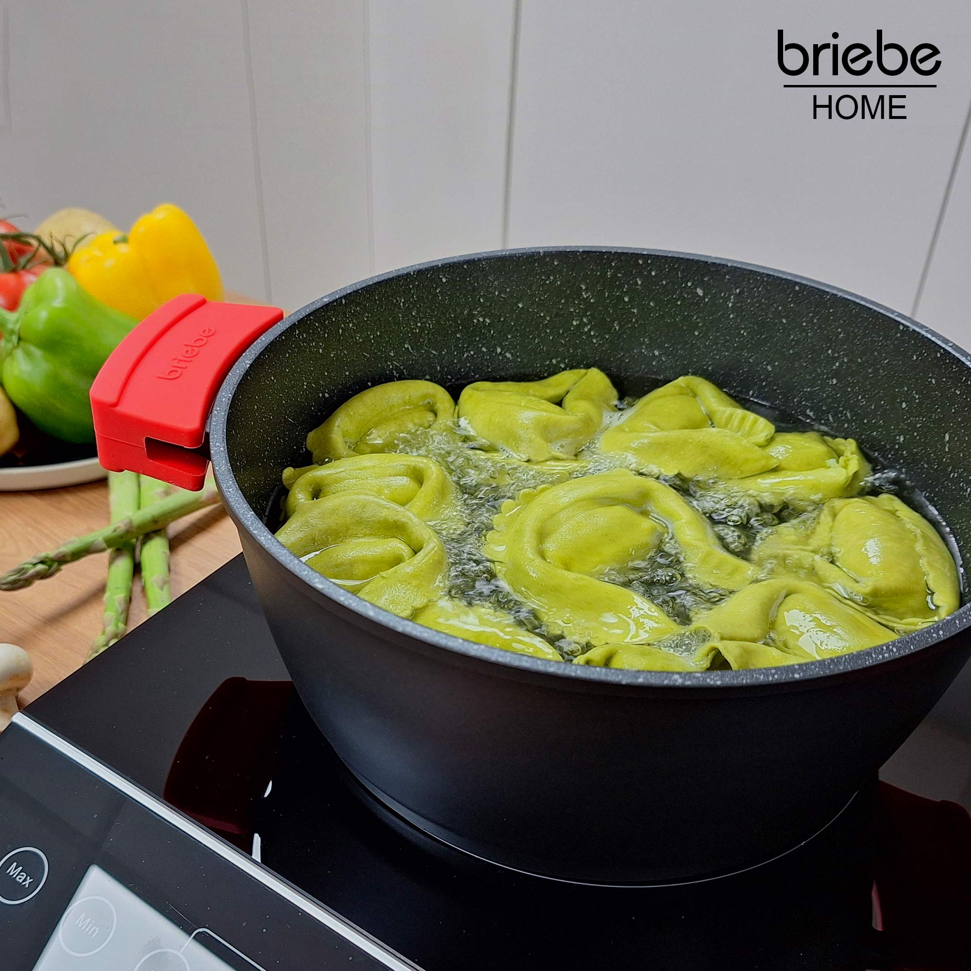 Tortellini verdes hirviendo en agua en una olla negra. Verduras y logo Briebe visibles.
