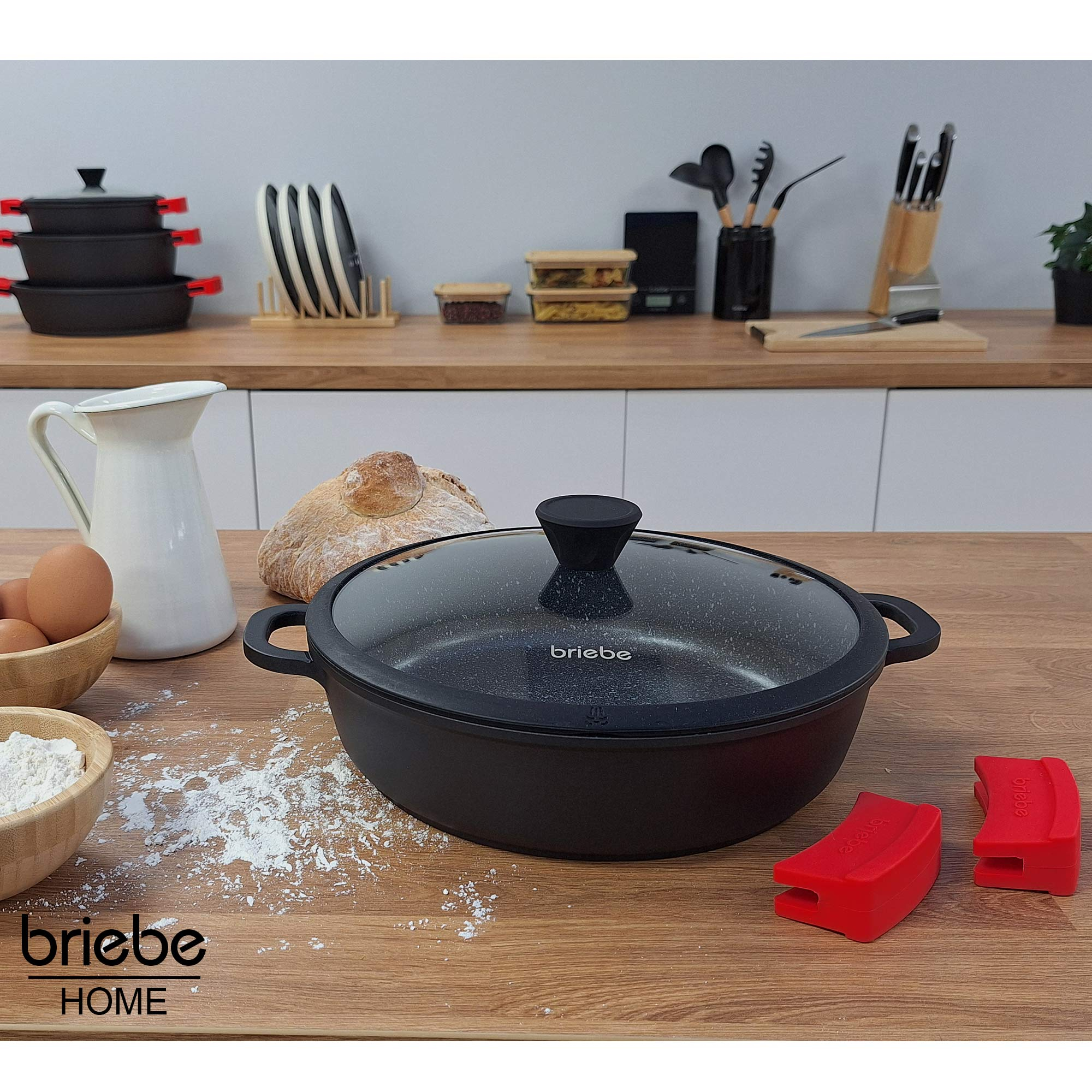 Olla negra con tapa sobre una mesa de madera, entorno de preparación de alimentos.