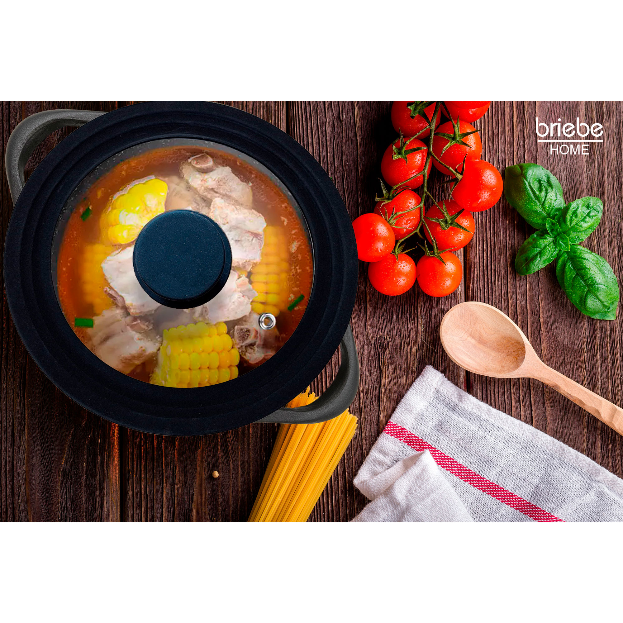 Una olla con comida dentro, tomates, albahaca y pasta sobre una superficie de madera.
