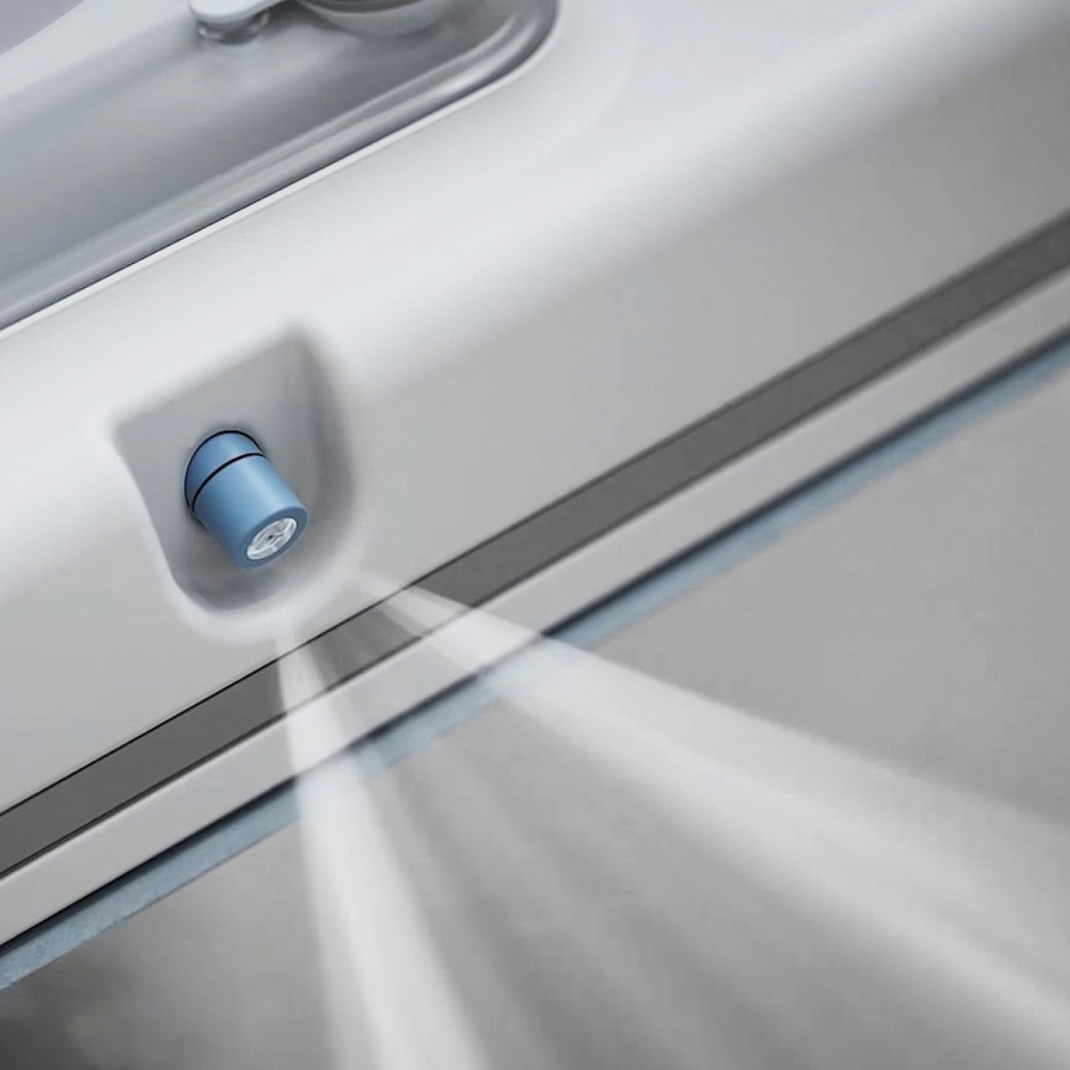 Un primo piano di un dispositivo bianco con una luce blu emessa da un ugello. Sembra uno strumento per la pulizia.