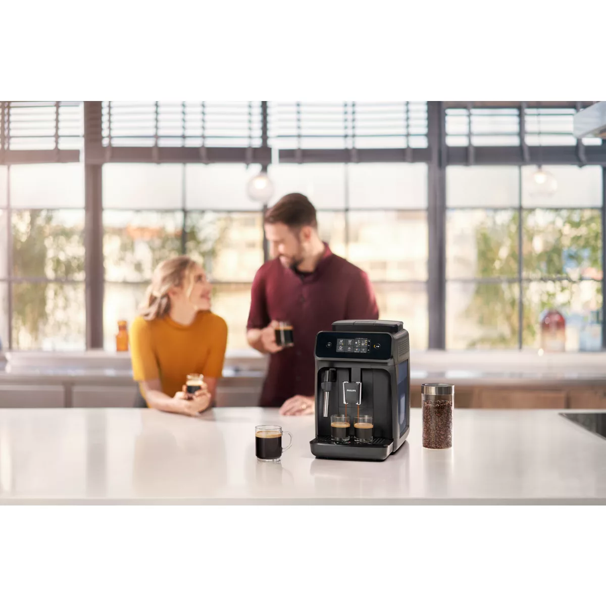 Ein Paar bereitet Kaffee mit einer schwarzen Espressomaschine zu, mit Kaffeebohnen und Tassen.