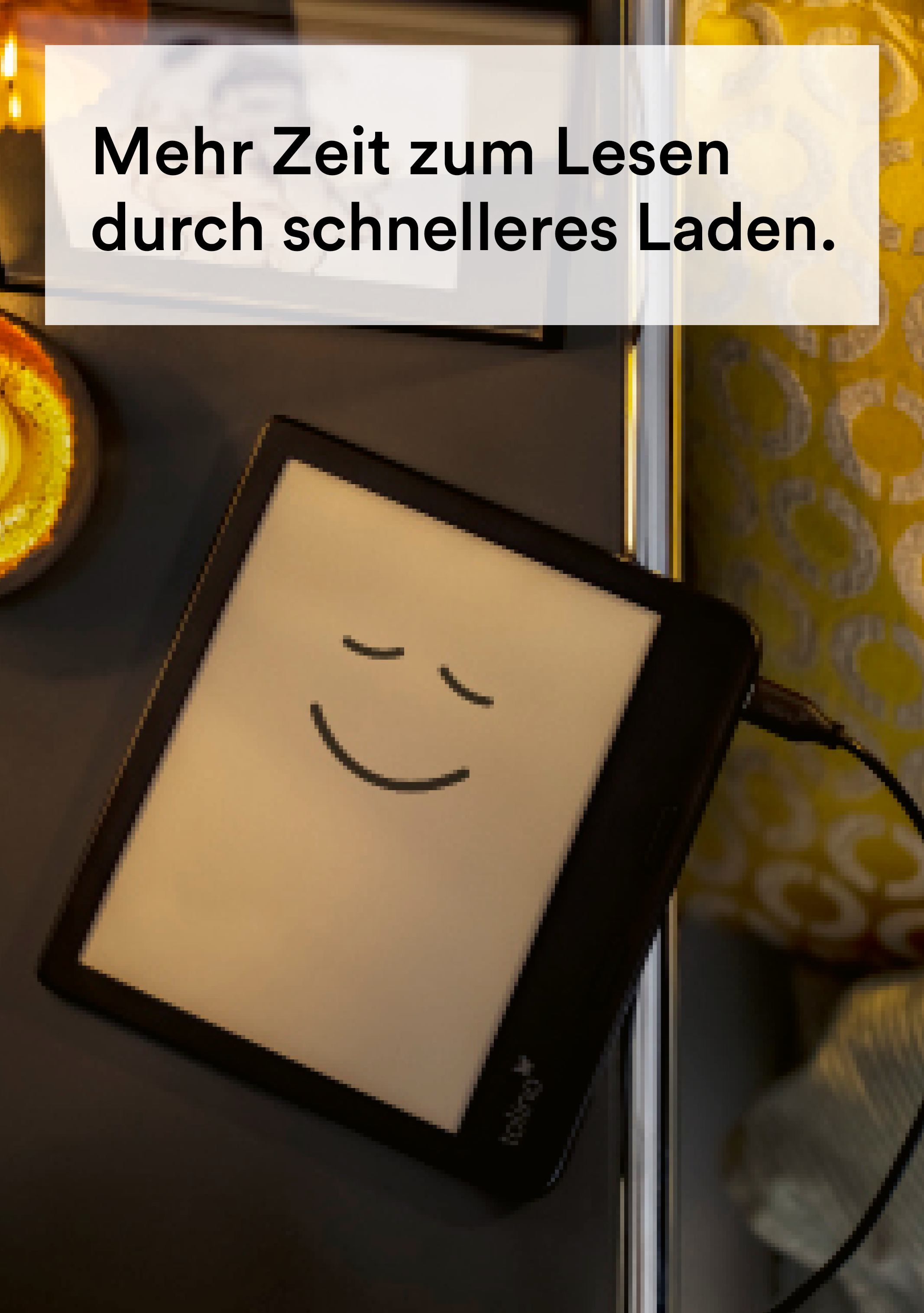 Czytnik e-booków z uśmiechniętą buzią na ekranie, na ciemnej powierzchni z tekstem u góry.