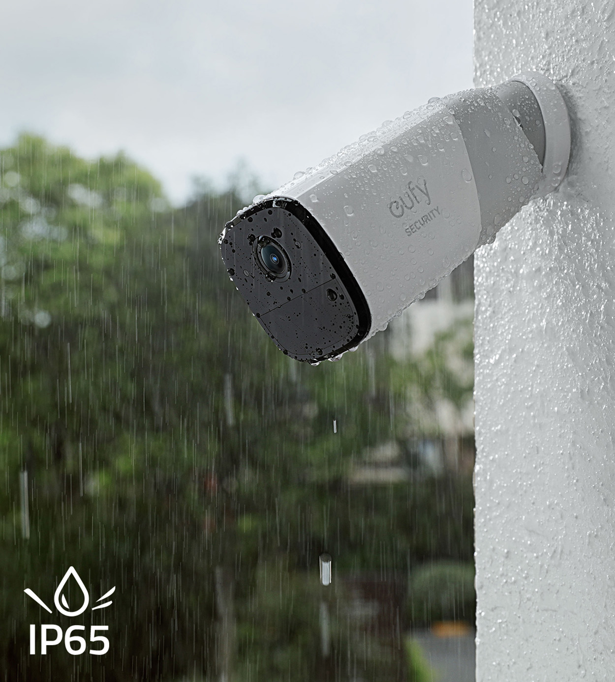 Una telecamera di sicurezza bianca montata su un muro con gocce di pioggia, con il testo IP65 sotto.
