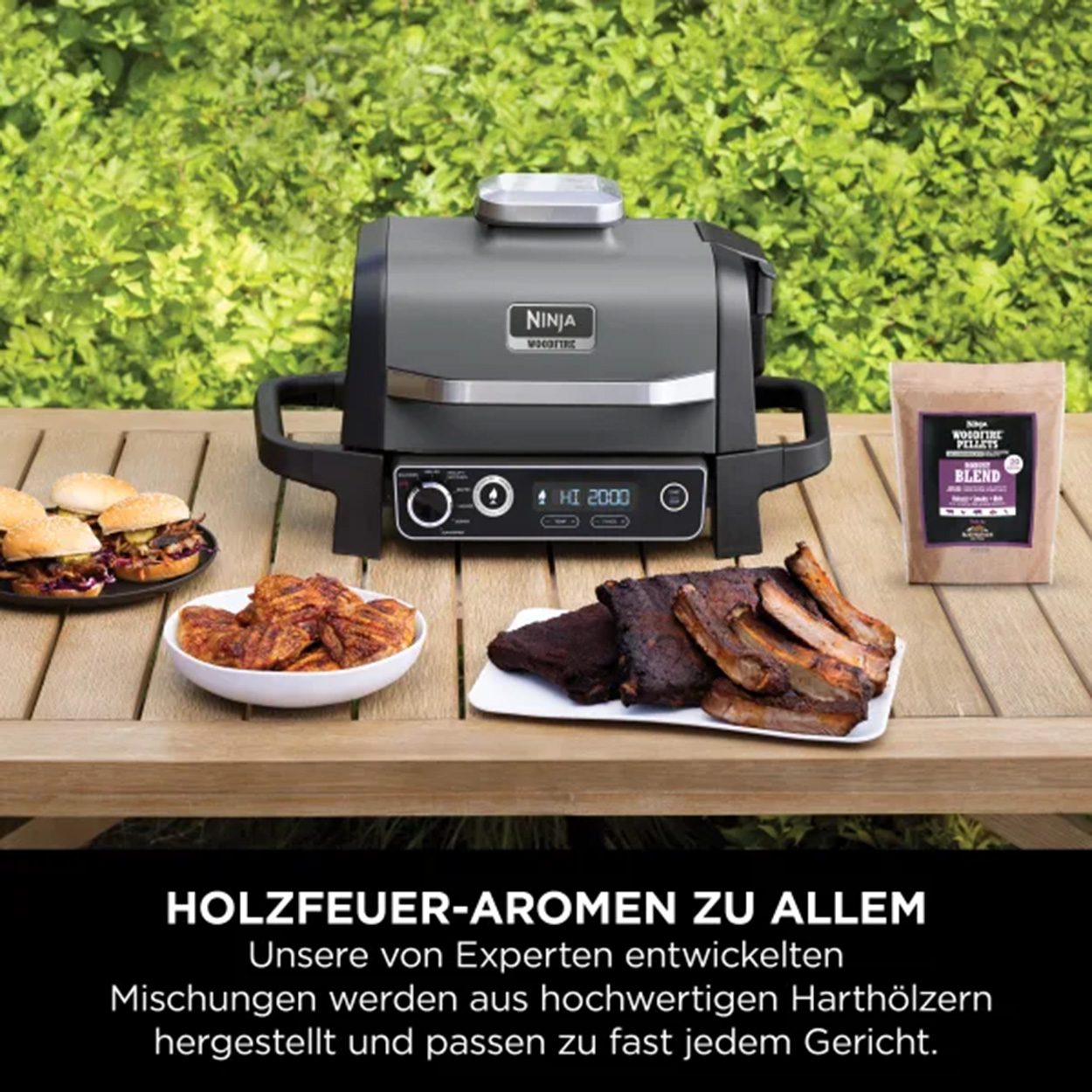 Grill Ninja Woodfire z jedzeniem na stole. Burgery, żeberka i dodatki z workiem pelletu.