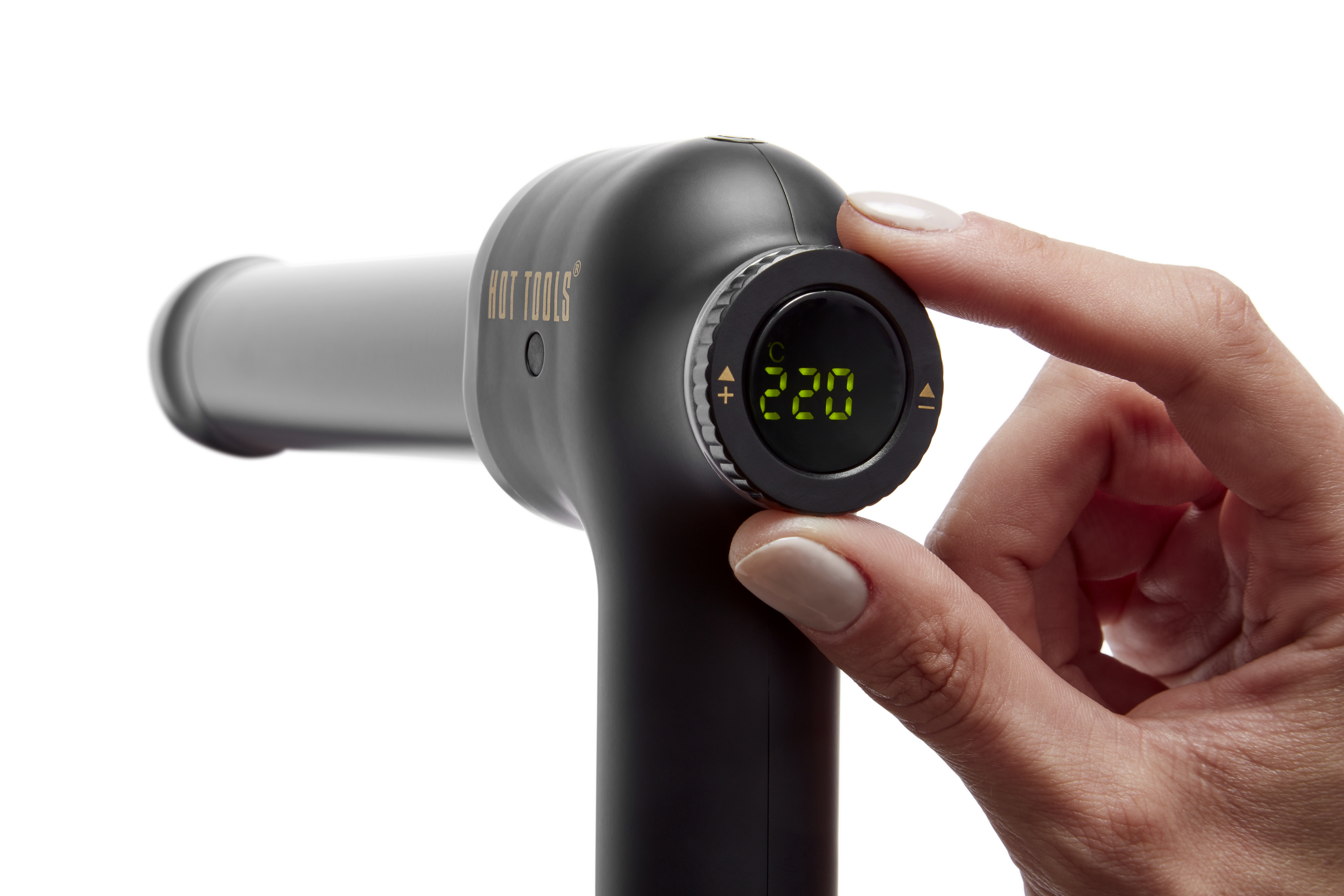 Een hand stelt de temperatuurknop van een zwarte Hot Tools krultang in op 220 graden.