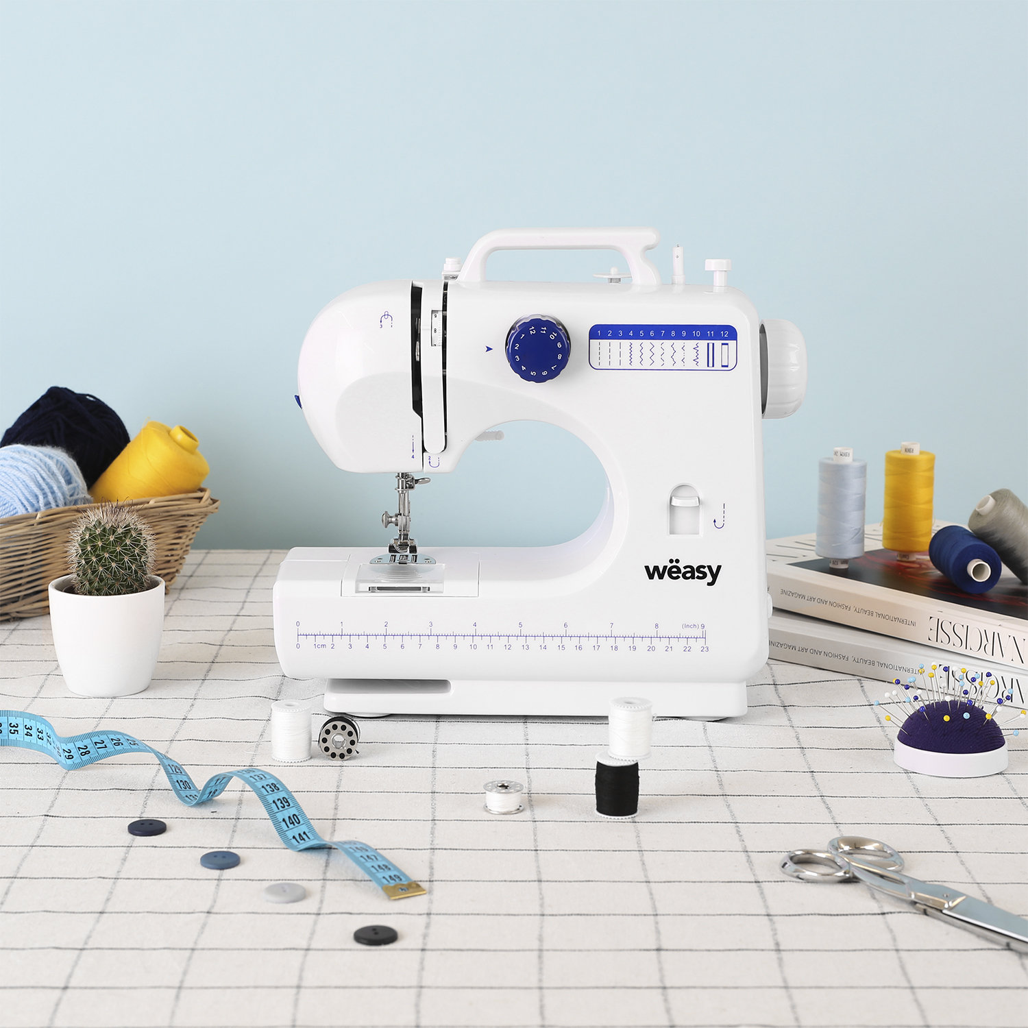 Biała maszyna do szycia z akcesoriami na kraciastej serwetce.