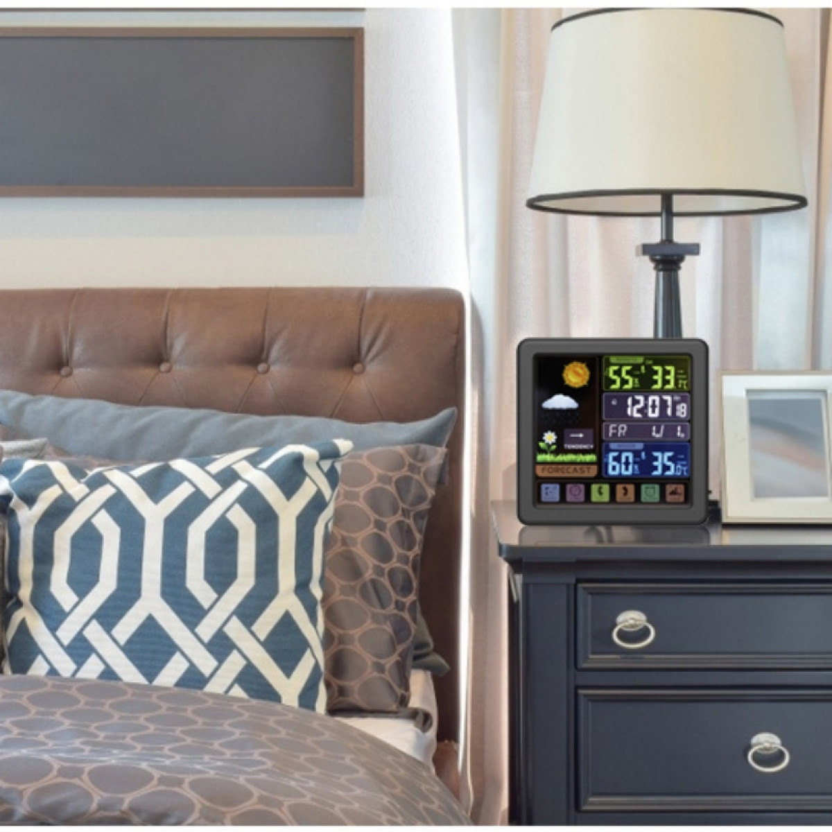 Stacja pogodowa na stoliku nocnym z cyfrowym wyświetlaczem pokazującym dane pogodowe, łóżko w tle.