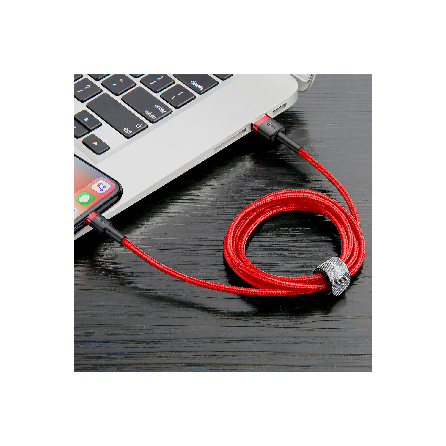 Czerwony kabel do ładowania USB-C podłączony do laptopa i smartfona. Kabel jest zwinięty.