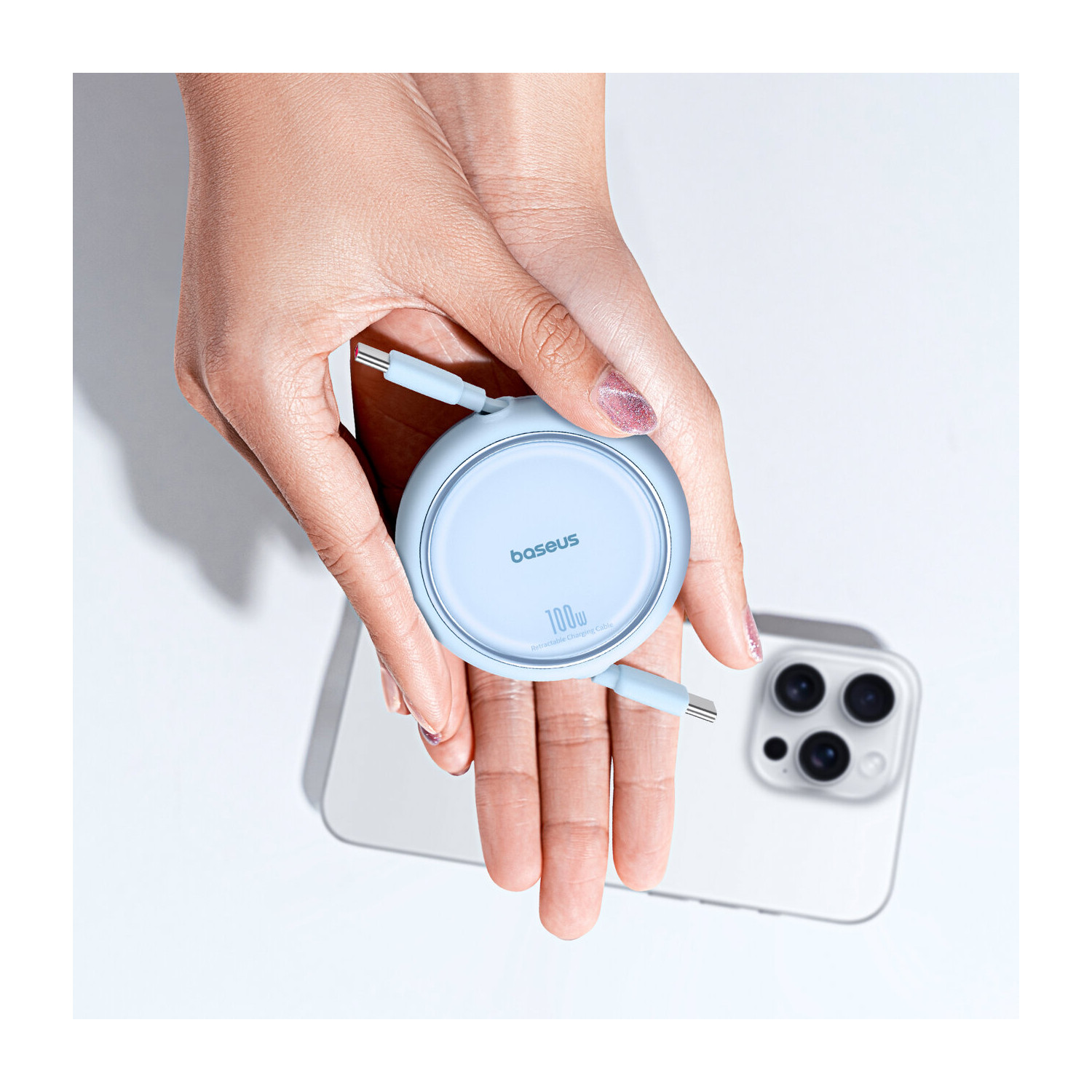 Jasnoniebieska okrągła ładowarka bezprzewodowa z kablem USB-C, trzymana przez osobę, z telefonem.