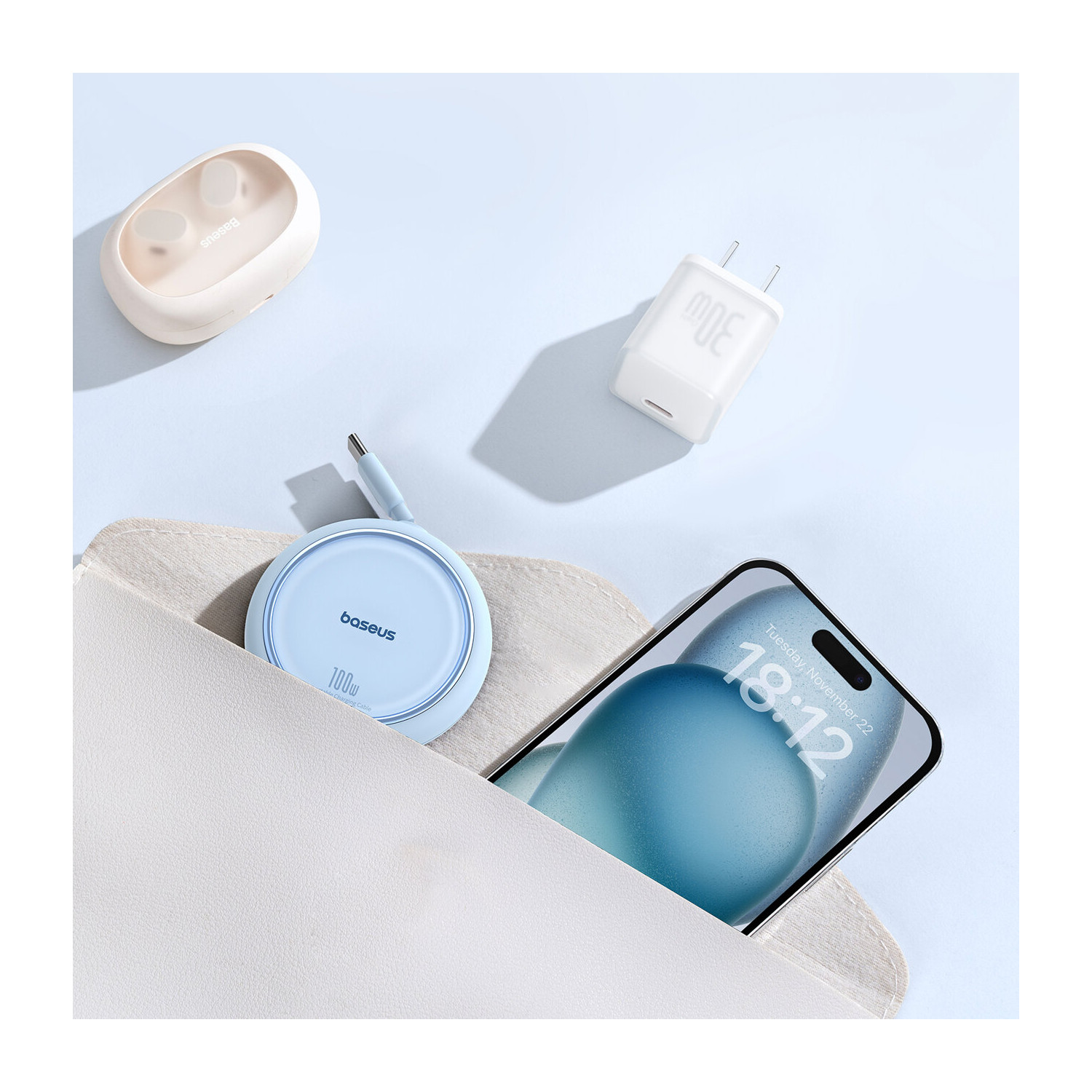 Niebieska ładowarka bezprzewodowa, telefon i ładowarka na jasnoniebieskiej powierzchni.