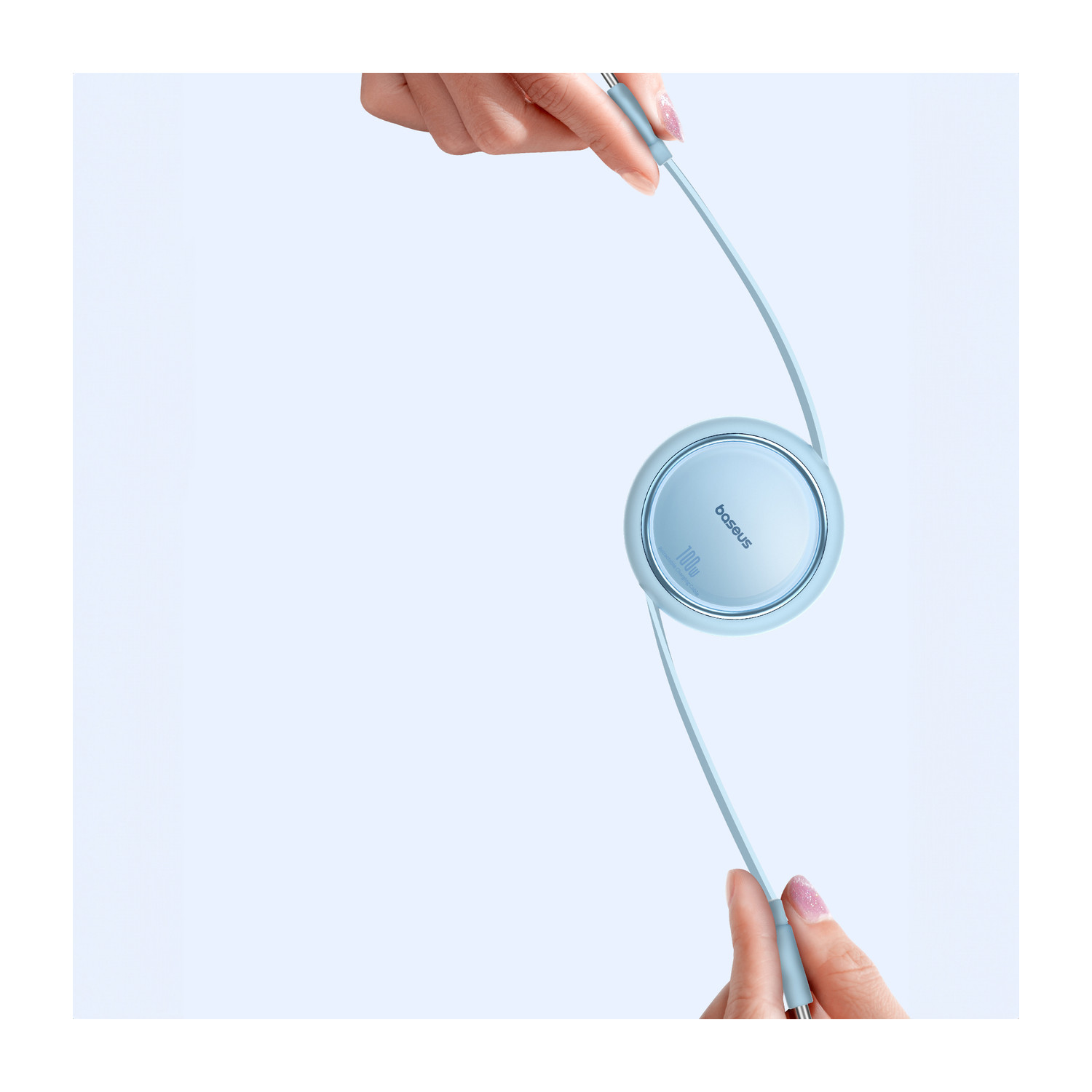 Jasnoniebieska ładowarka Baseus z dwoma niebieskimi kablami w dłoniach.