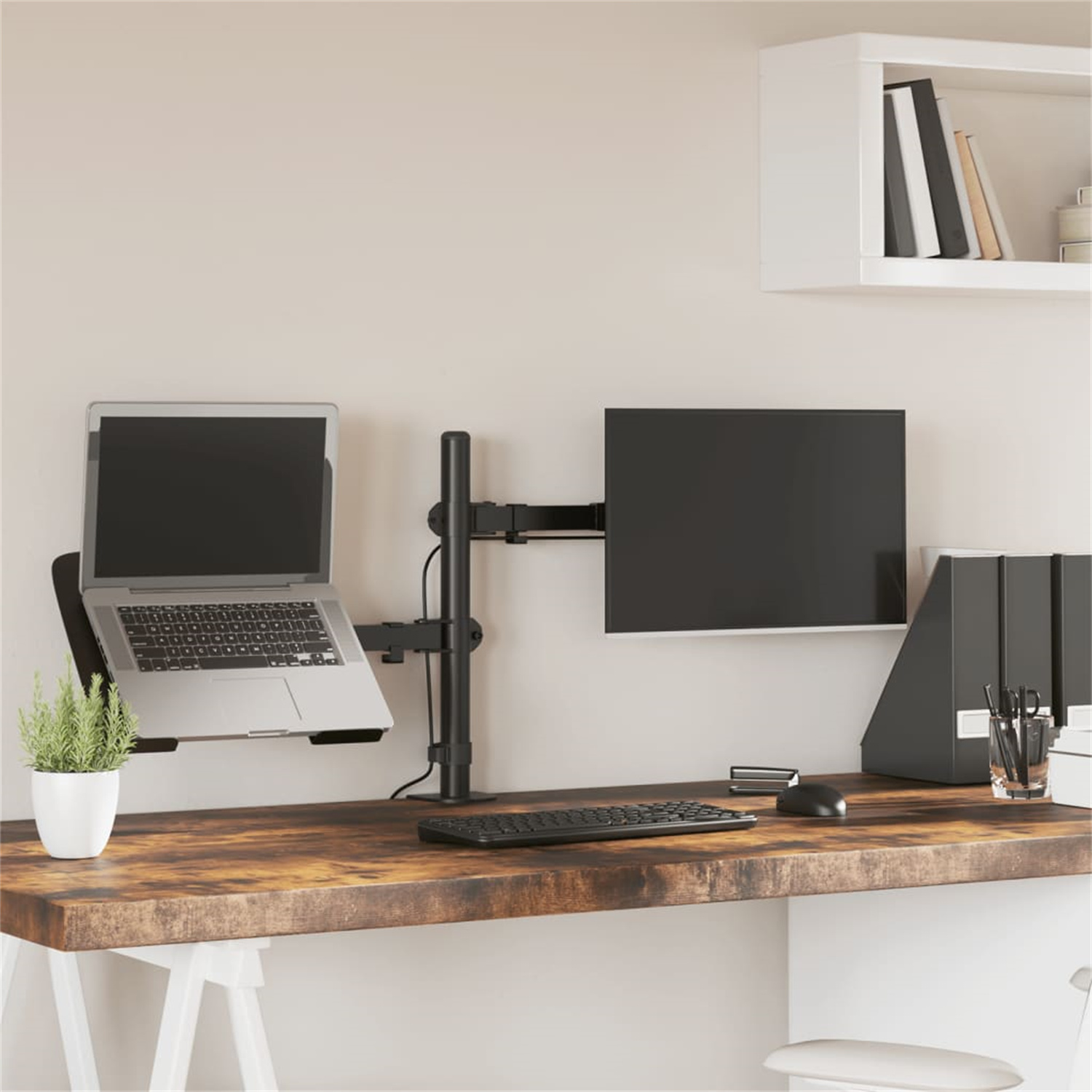 Arbeitsplatz mit Laptop, Monitor und Schreibtisch. Pflanzen und Büromaterial sind sichtbar.