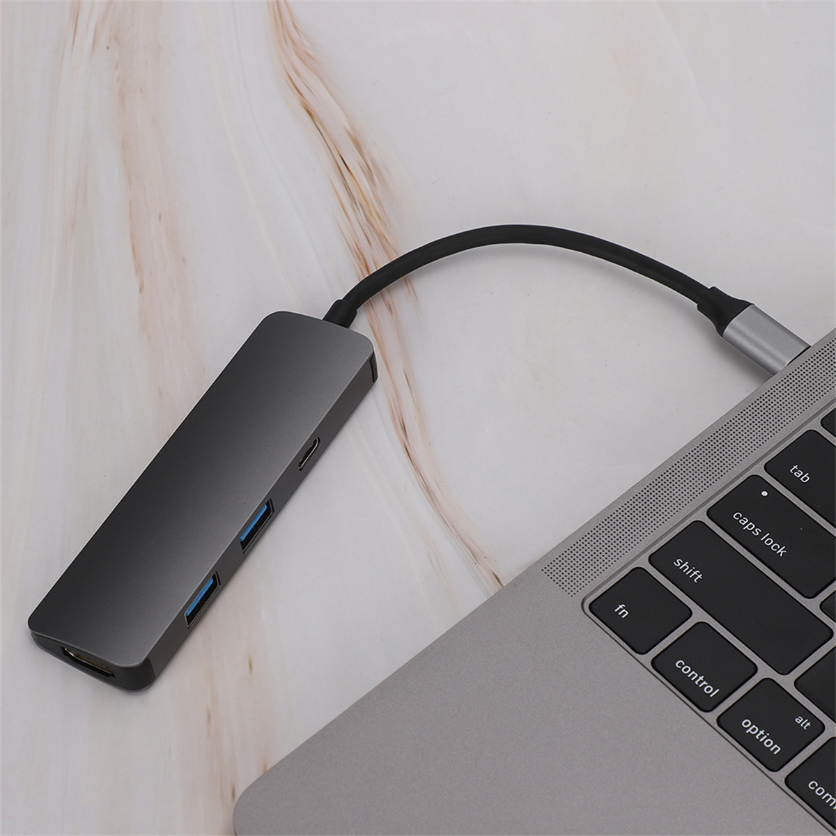 Ein grauer USB-Hub, der an einen Laptop angeschlossen ist. Es hat USB-Anschlüsse, HDMI und einen USB-C-Anschluss.