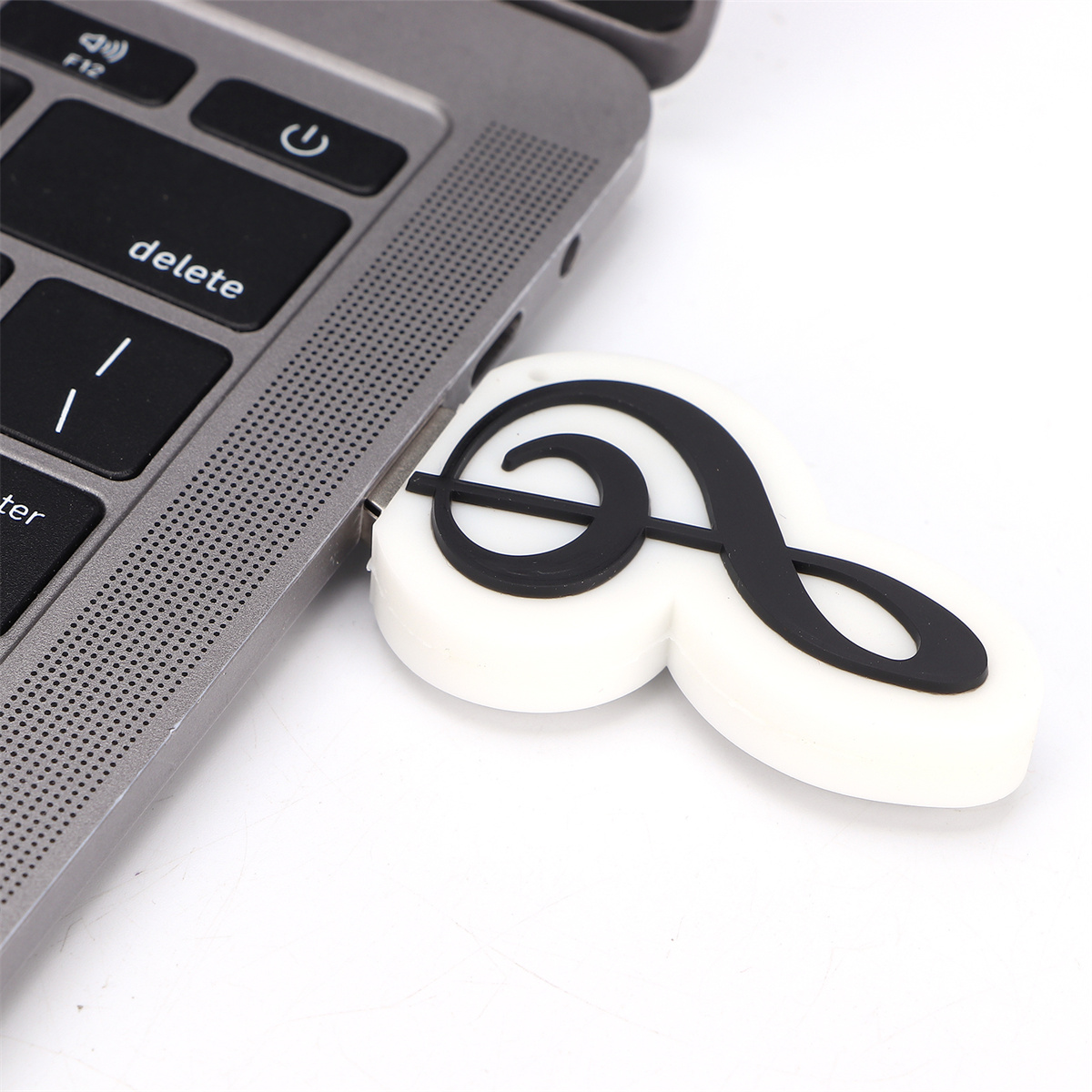 Ein Laptop mit einem eingesteckten USB-Stick. Der USB-Stick ist weiß mit einem schwarzen Notenschlüssel-Design.