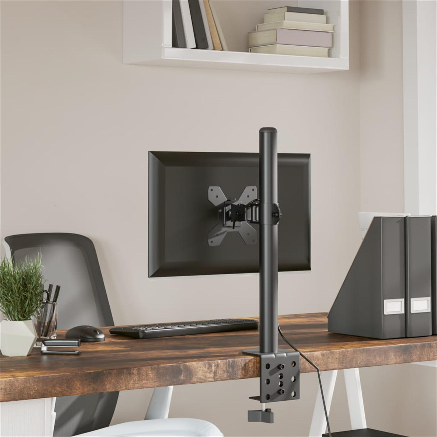 Ein Computermonitor, der an einem schwarzen Ständer befestigt ist. Der Ständer ist auf einem Holztisch montiert.