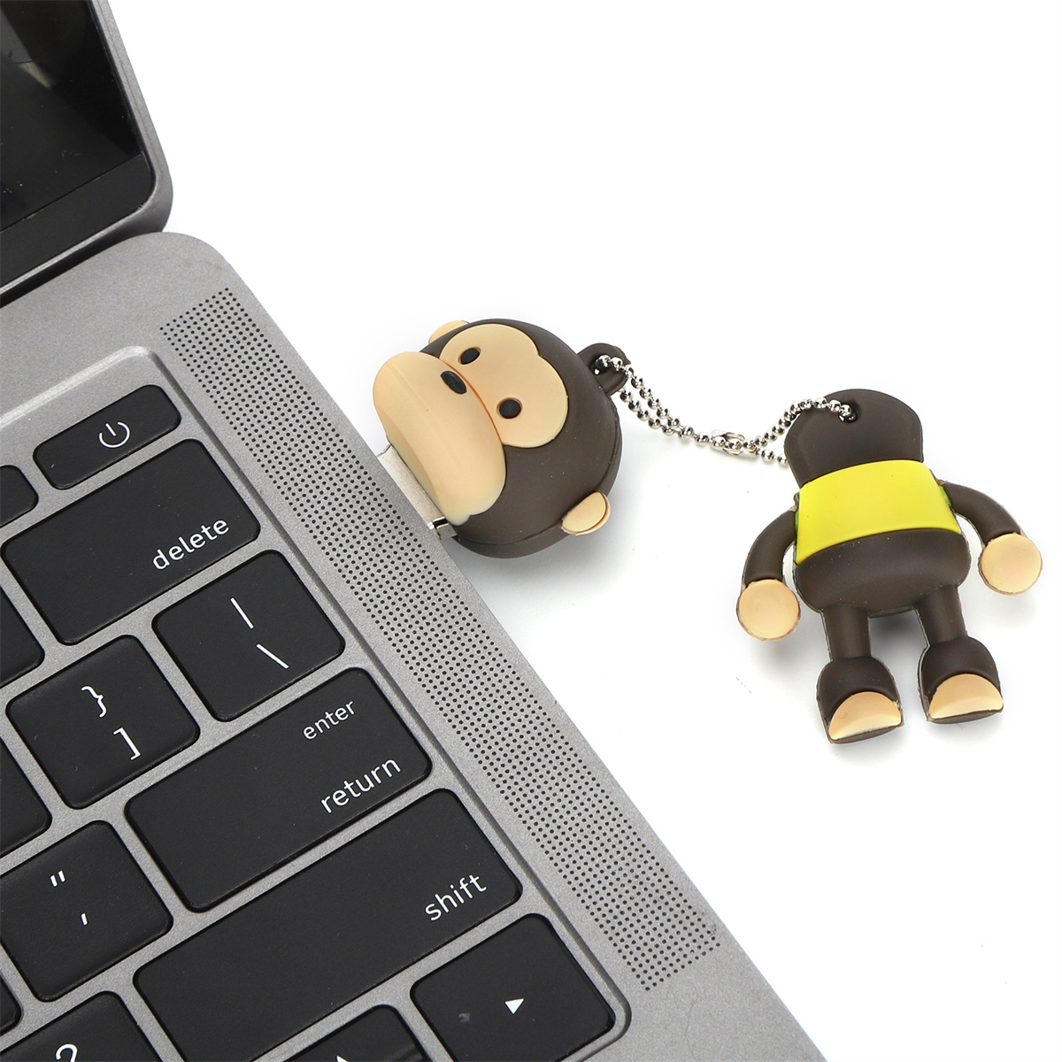 Ein affenförmiger USB-Stick, der an einen Laptop angeschlossen ist, mit einer passenden Schlüsselanhängerfigur.
