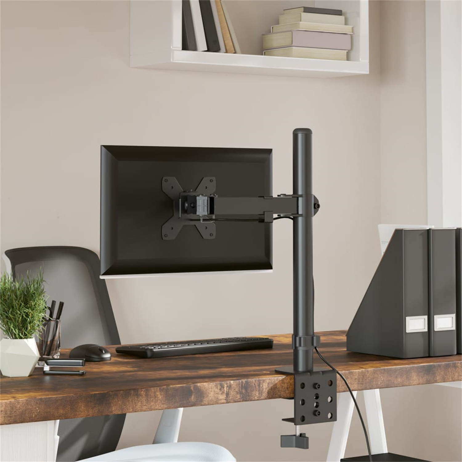 Ein schwarzer Monitor ist auf einem Schreibtisch montiert. Der Schreibtisch hat einen Monitorarm, eine Tastatur und andere Büroartikel.
